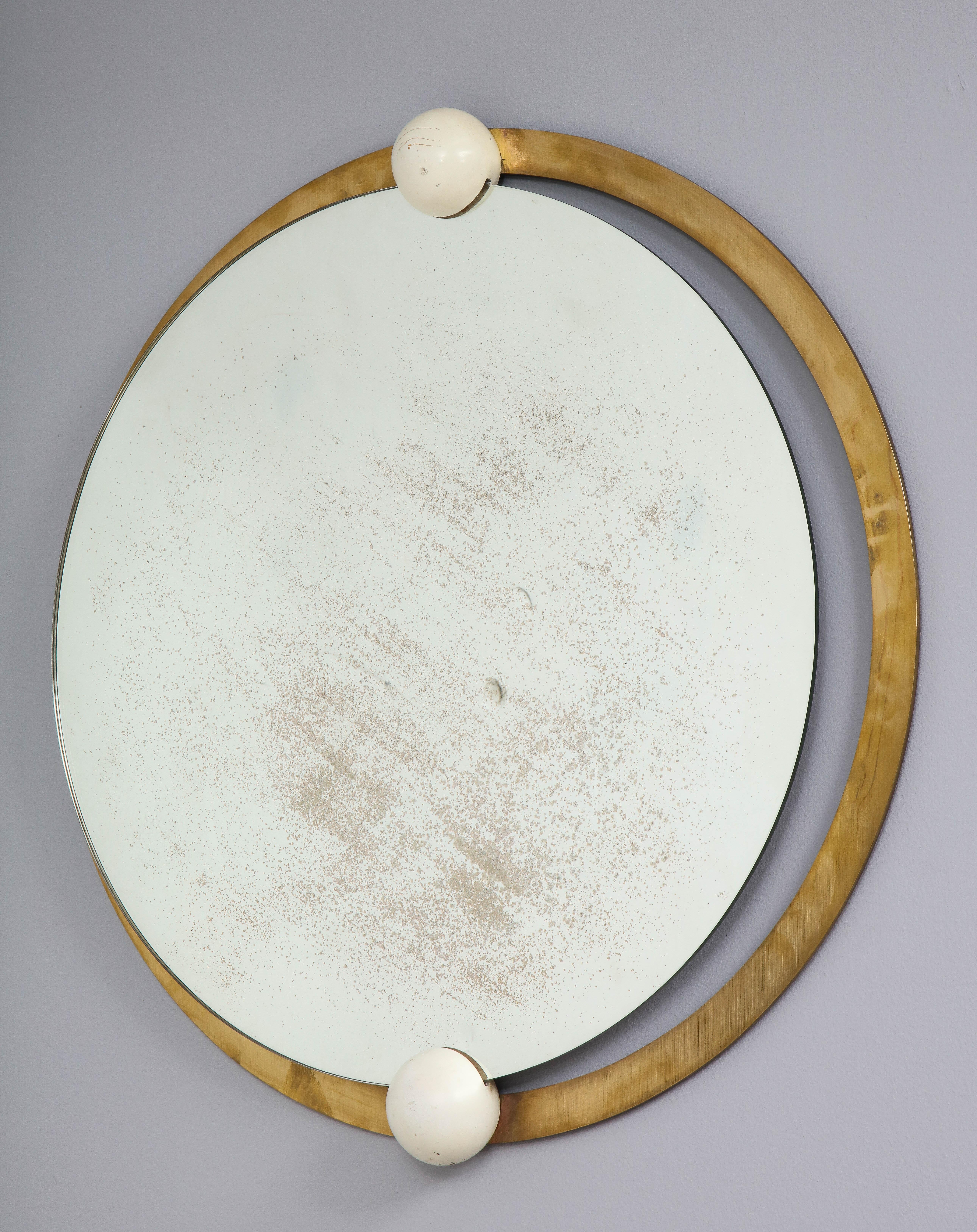 An Italian circular brass mirror with two painted white wood decorative balls, the glass aged.
Italy, circa 1960
Size: 26 1/4