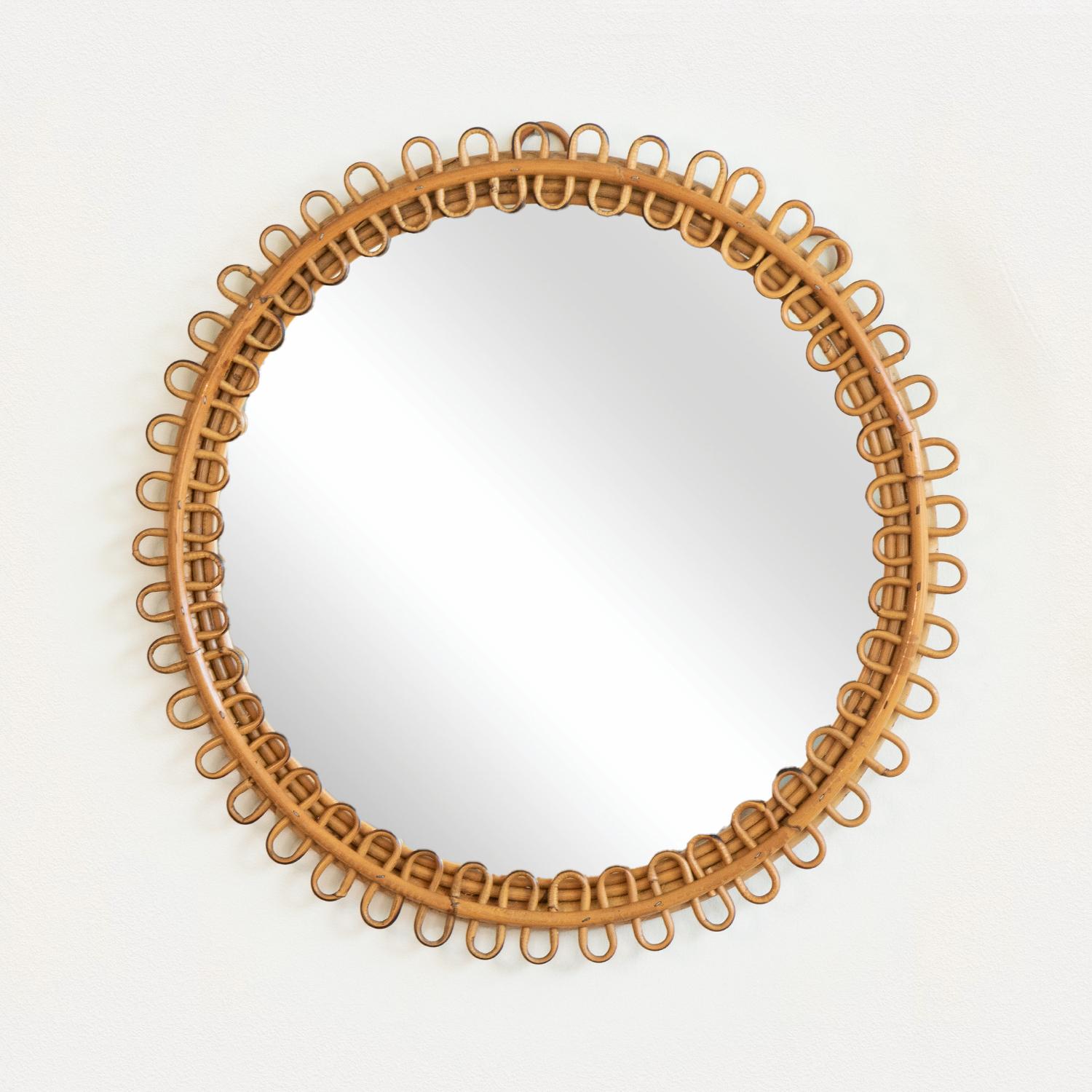 Beautiful rattan mirror in an oval shape from Italy, 1960s. Unique design with looped rattan detailing encompassing the mirror. Statement piece perfect for bathroom or entryway. Nice vintage condition with original coloring and original mirror.
