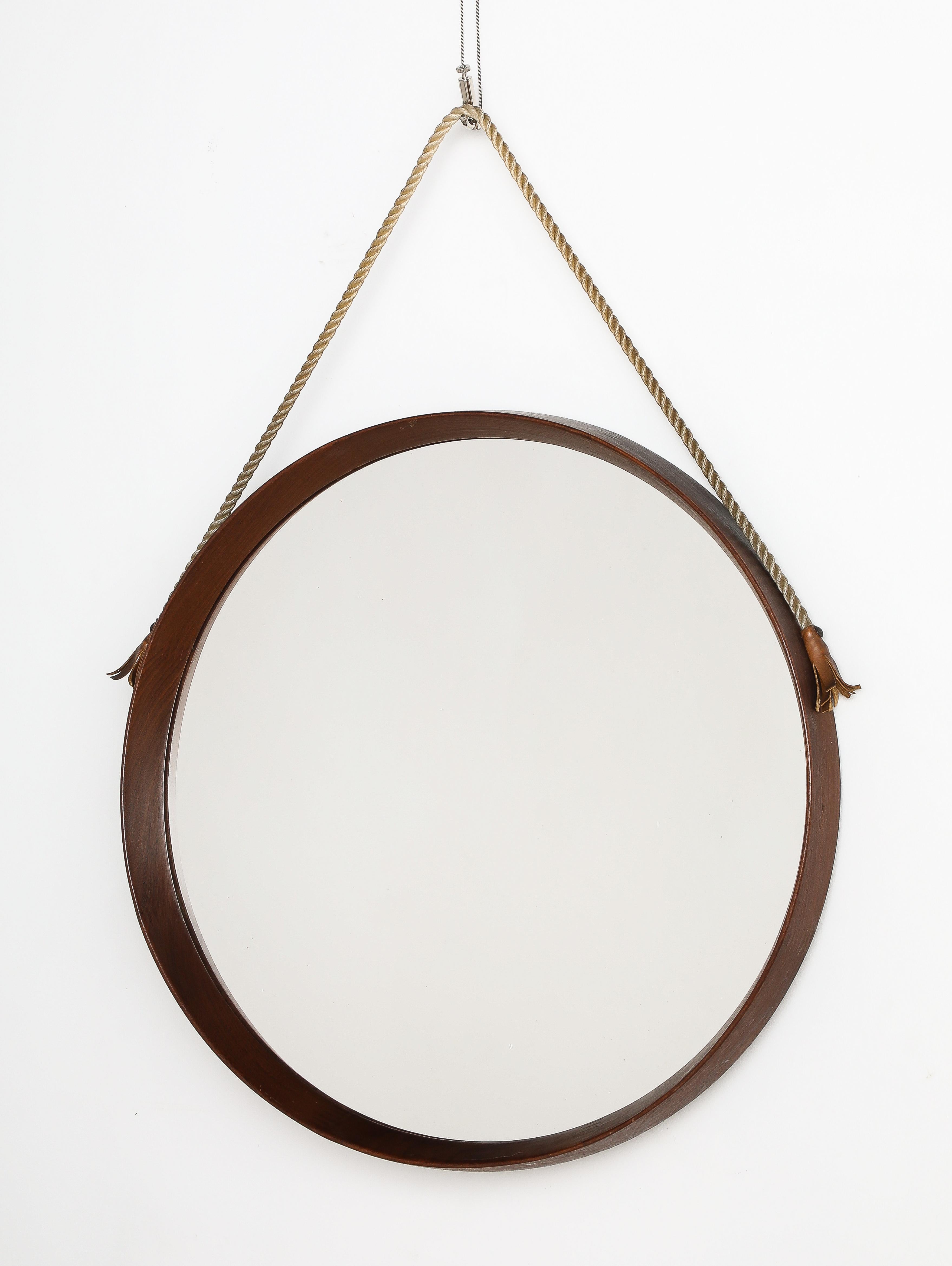 A charming Italian modernist circular teak hanging wall mirror with rope strap adhered to the frame with leather tassels.  
Italy, circa 1960 
Size: 20