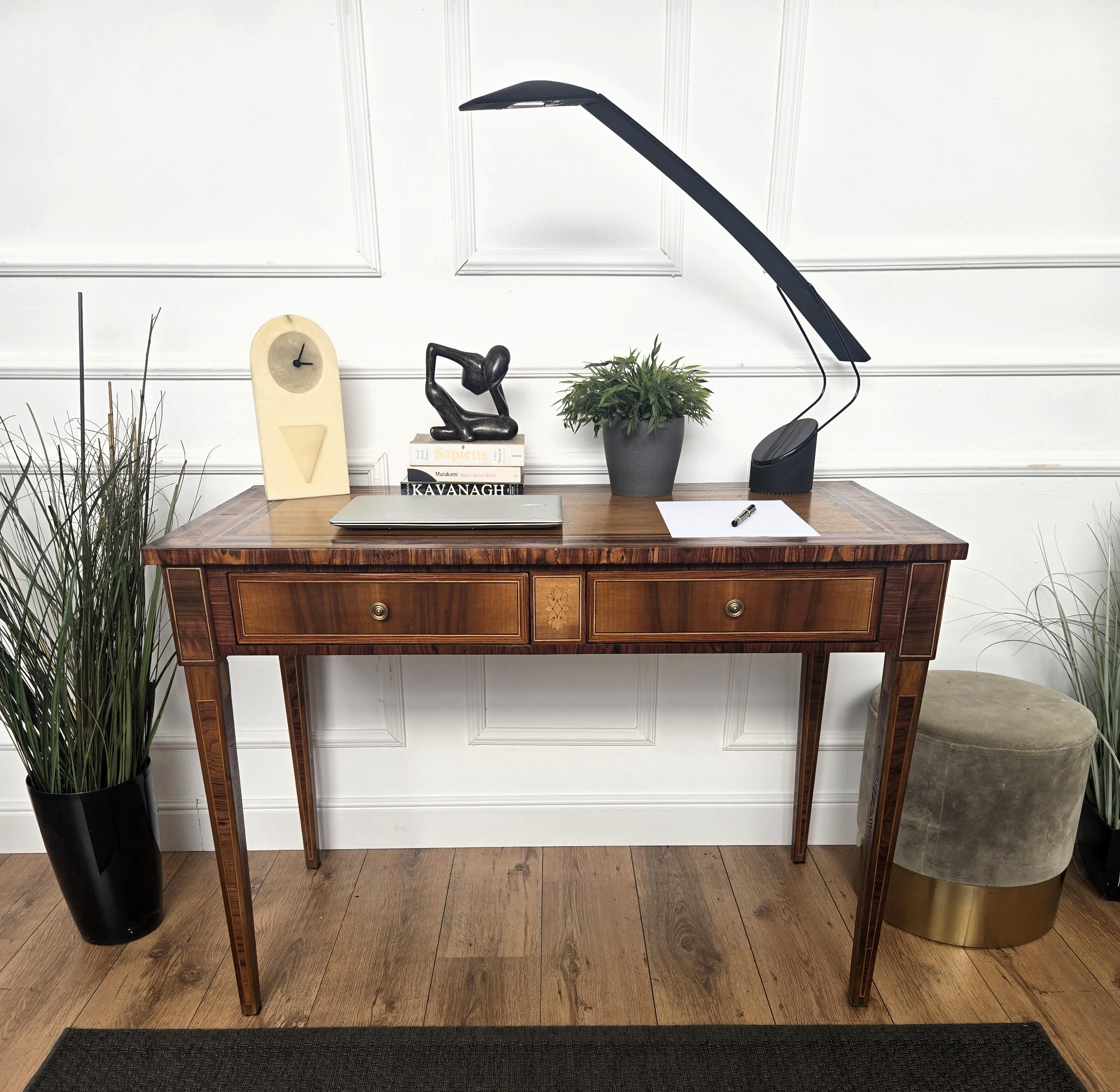 Very elegant Italian desk writing table with amazing veneer wood marquetry decorations, double central drawers and nicely carved legs. This piece impresses with its intricate marquetry work and timeless craftsmanship. The tabletop features a