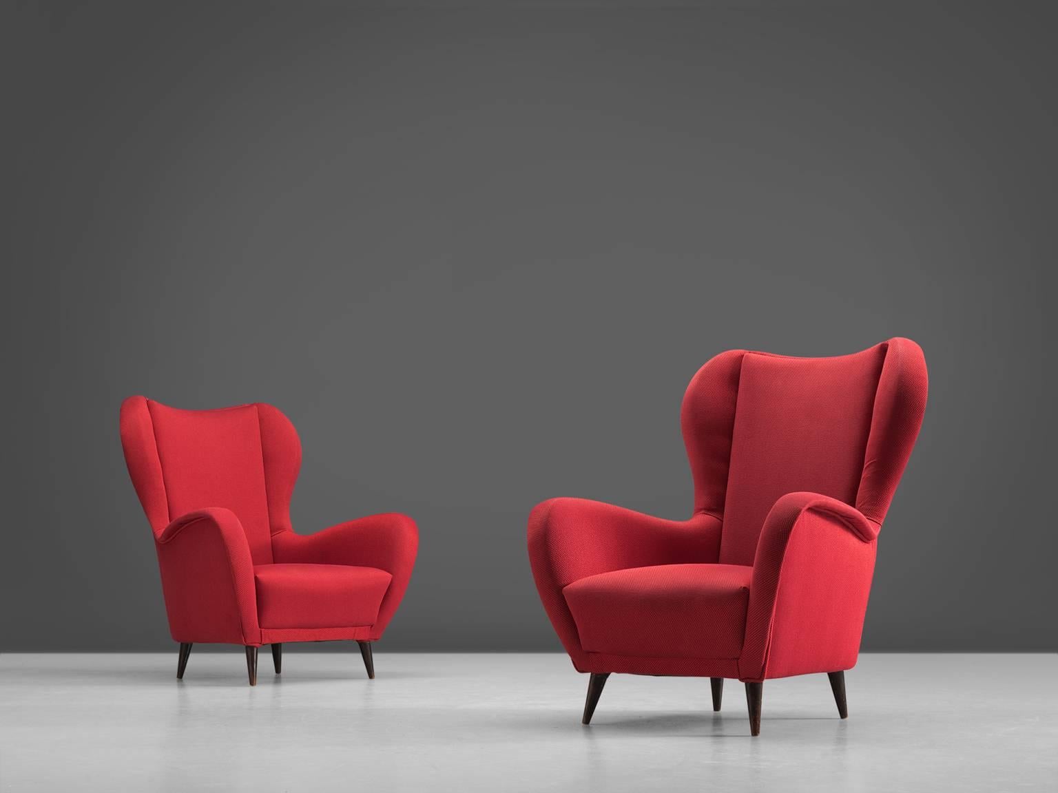 Pair of armchairs, red fabric, wood, Italy, 1950s.

These lounge chairs are both voluptuous and grand as they are comfortable. The chairs embody a semi-high wingback composed of curvaceous lines. The design fits perfectly into the Italian ethos of