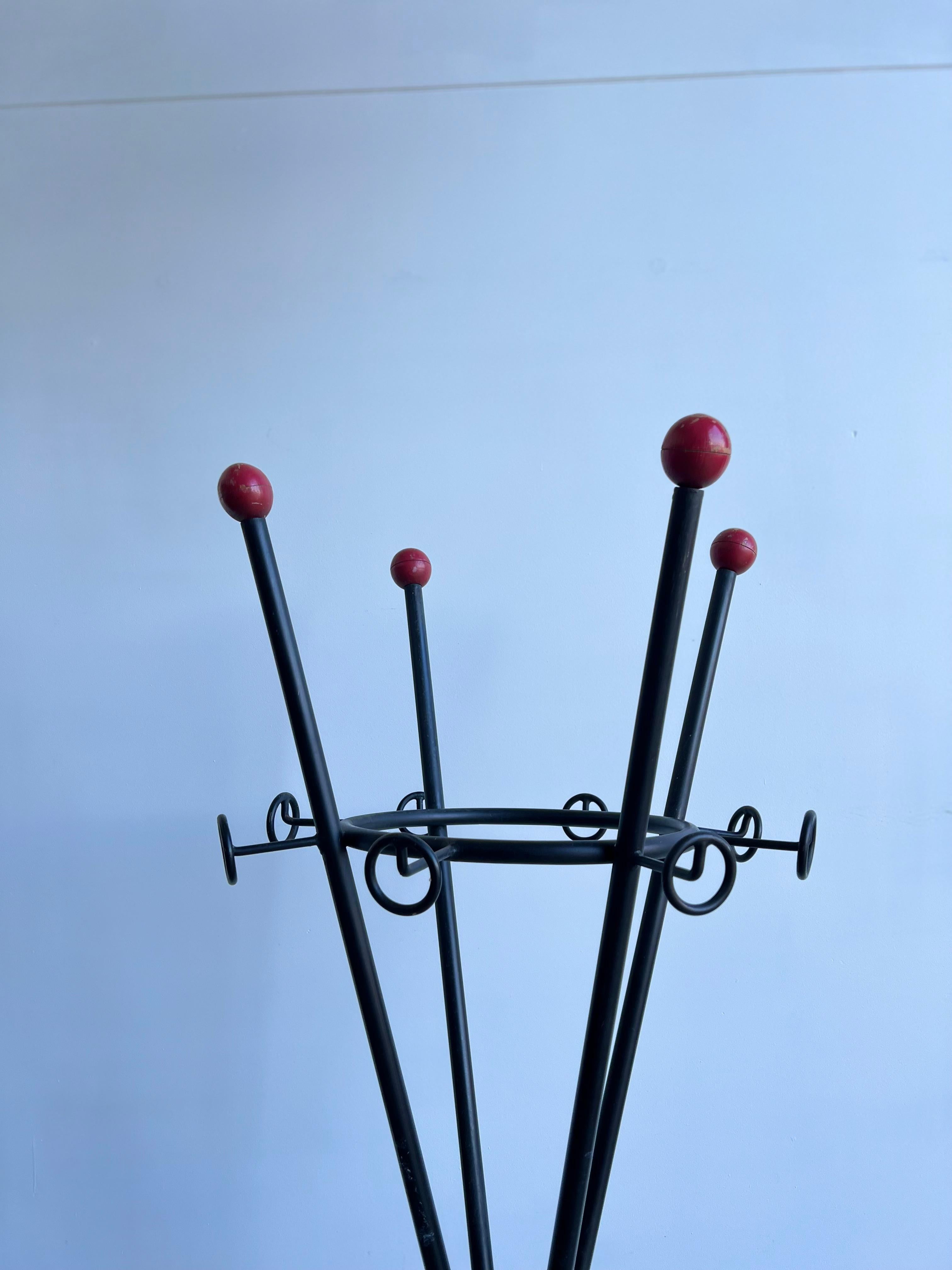 Italian 1980s coat rack in black metal and wood red balls.
Coat rack 1980s also umbrella holder on the mid section of the rack.
The top of the coat rack arms are refine with red timber balls on the.
 