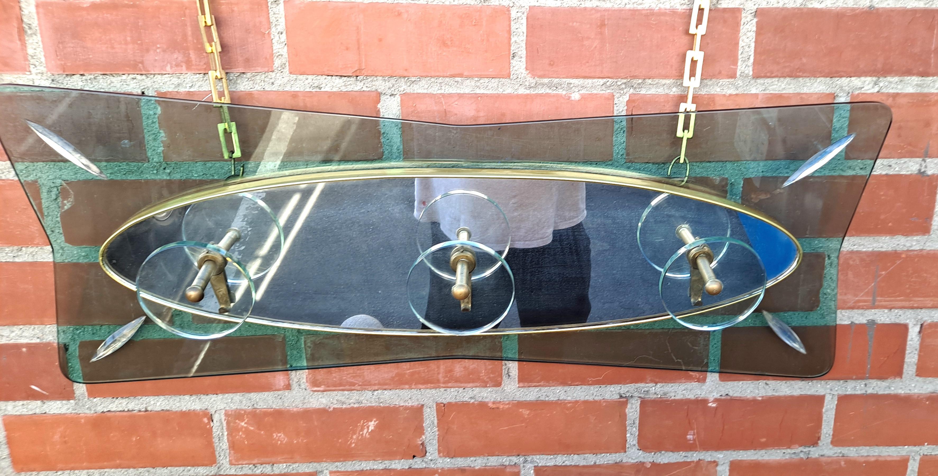 Mid-Century glass wall coat rack combine modern design with traditional craftsmanship. It is an excellent addition to any home.Rectangular panel of green fume glass  with large glass and brass hanging hooks. Manufacturer is Fontana Arte.  Very high