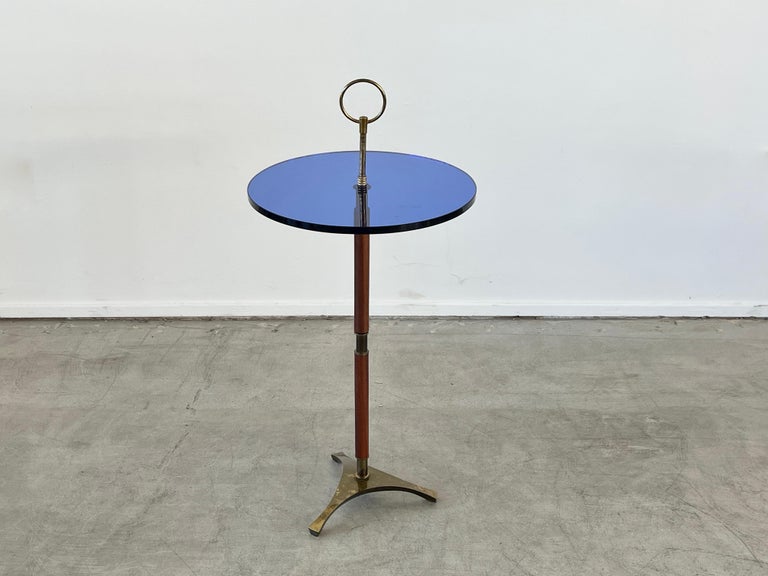 Fantastic cocktail table with original blue glass, leather base and cast brass tripod base with circle ring at the top.