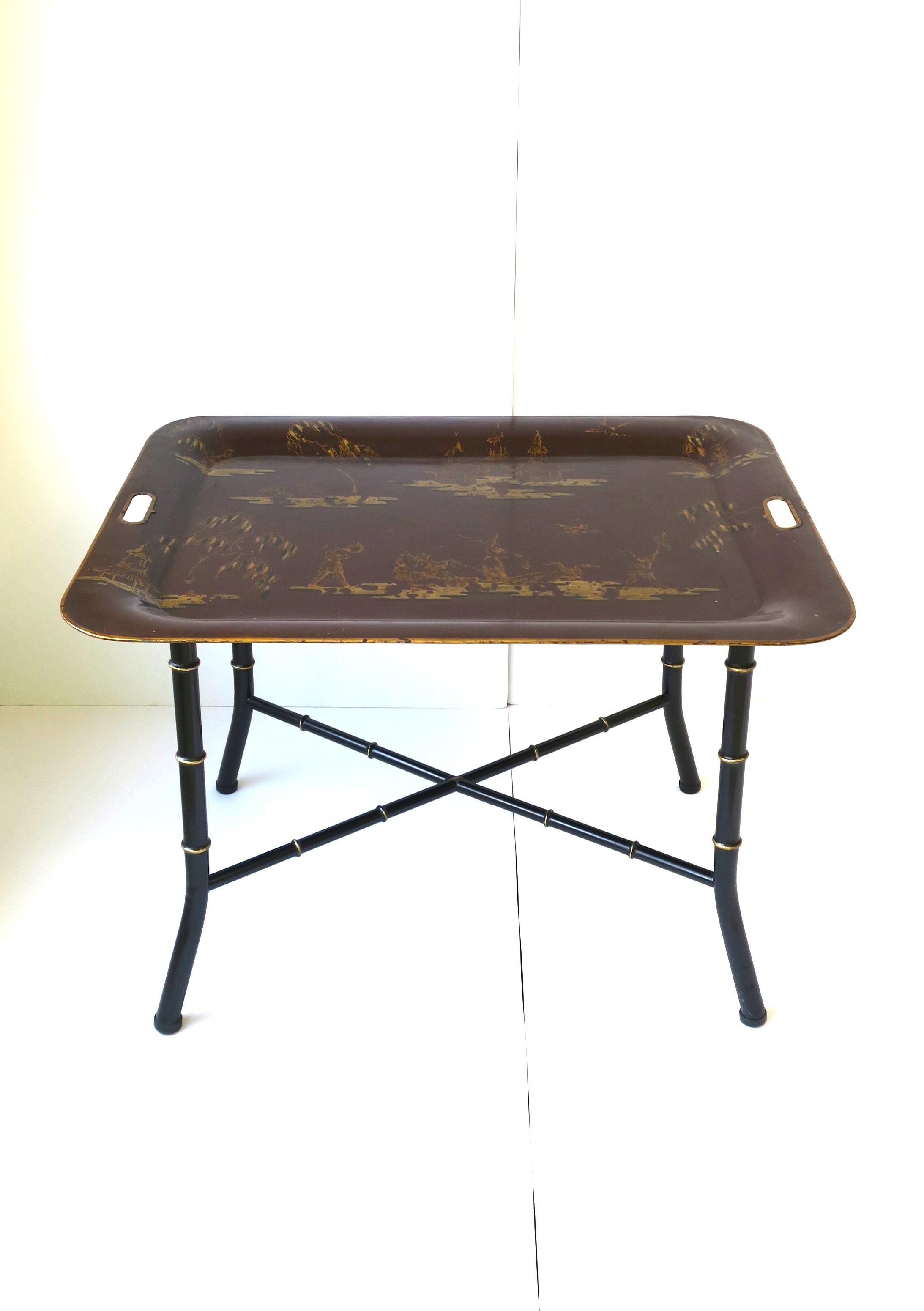 An Italian tray table cocktail table with a Chinoiserie tole tray top and black faux bamboo base, circa mid-20th century, Italy. Table tray is a red burgundy with a gold Chinoiserie landscape and figurative design. Table's base is a black and gold