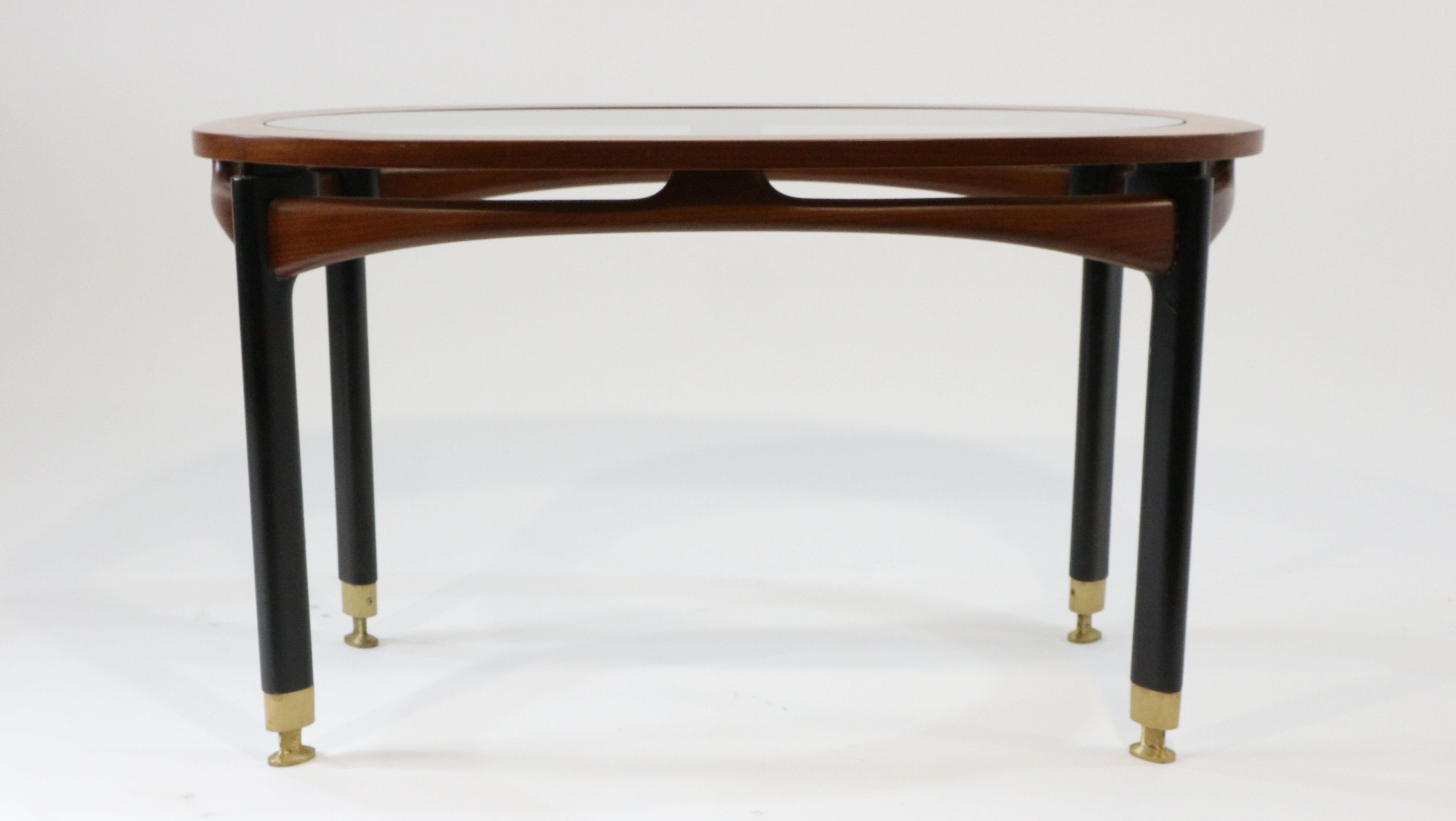 This coffee table, produced in the circa 1960.
Made whit wood, glass and brass.

The use of materials that sees the contrast of natural wood and painted in black whit feet made of brass in a very precise, make this coffee table a small jewel of the