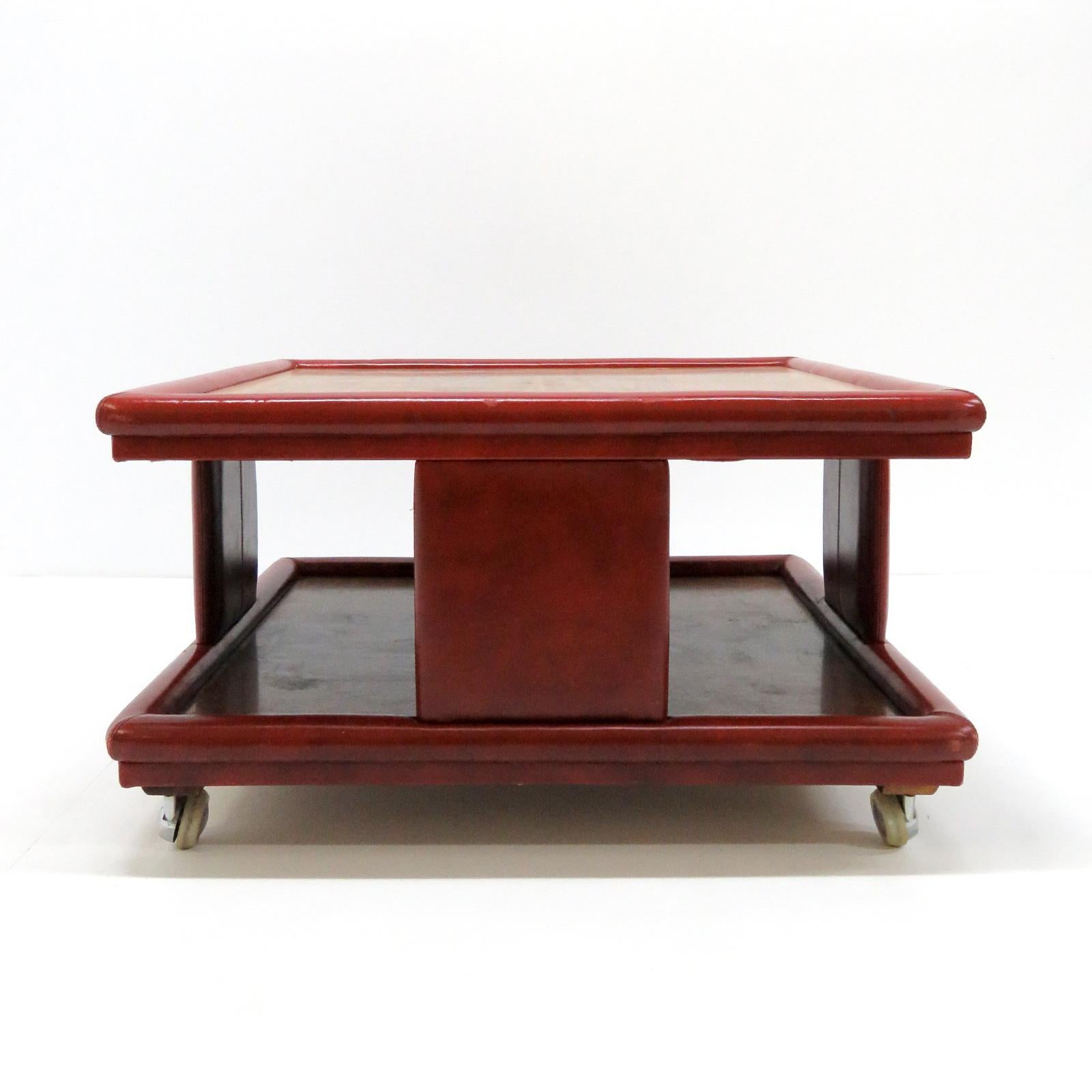 Wonderful red leather and wood two-tier coffee table from Italy, 1970, attributed to Poltrona Frau. One dark one light wood top, great patinaed leather cladding on detachable casters.
  