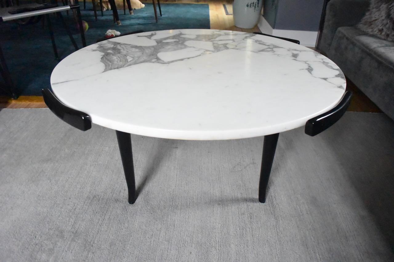 A marble-top coffee table with black lacquered wood base in the manner of Gio Ponti,
Italy,
1950s.
 