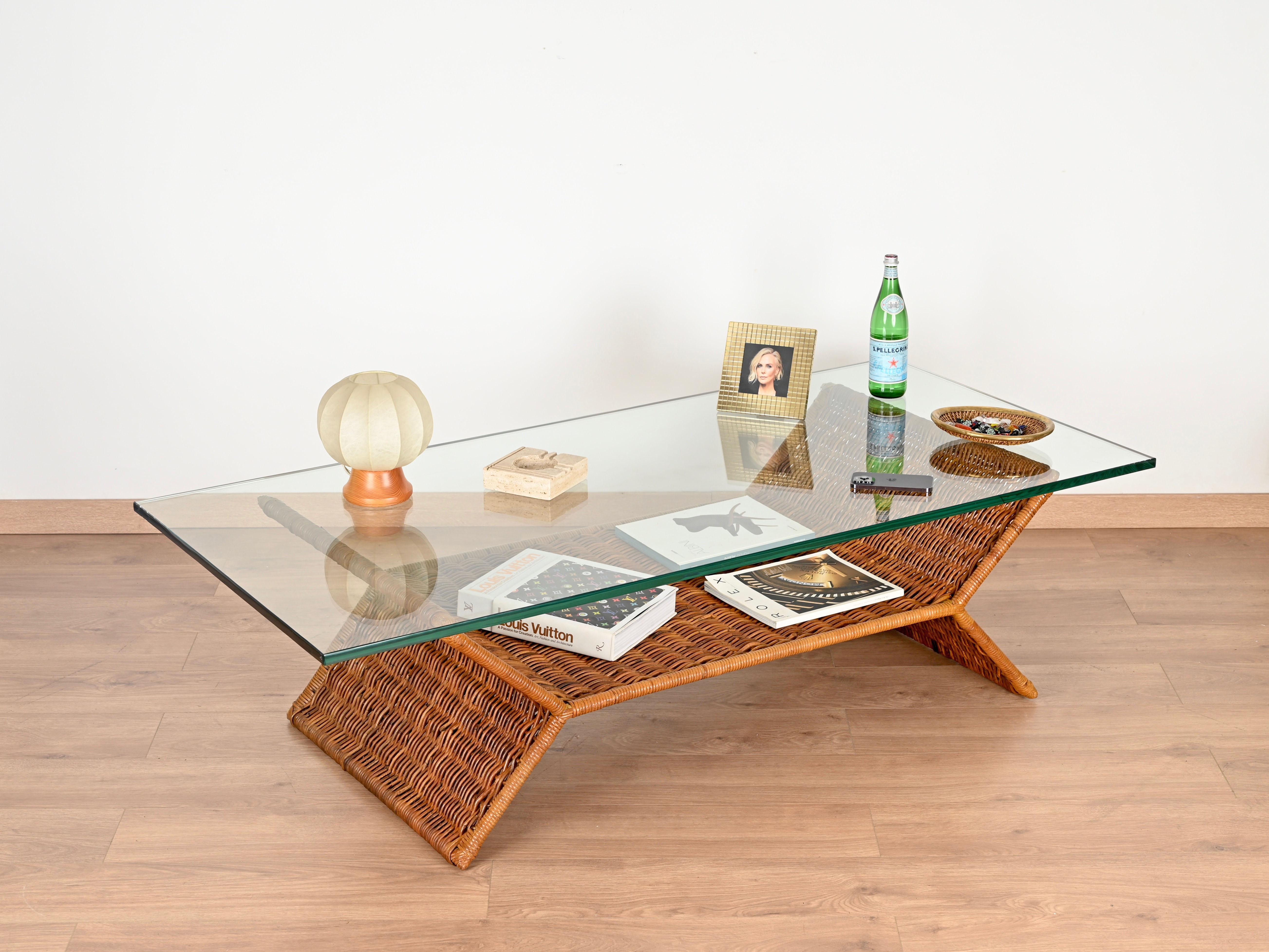 Splendido tavolino italiano di grandi dimensioni con portariviste interamente realizzato in rattan intrecciato a mano e completato da un fantastico piano in cristallo spesso 19 mm. Questo pezzo di stile è stato realizzato a mano da Vivai del Sud in