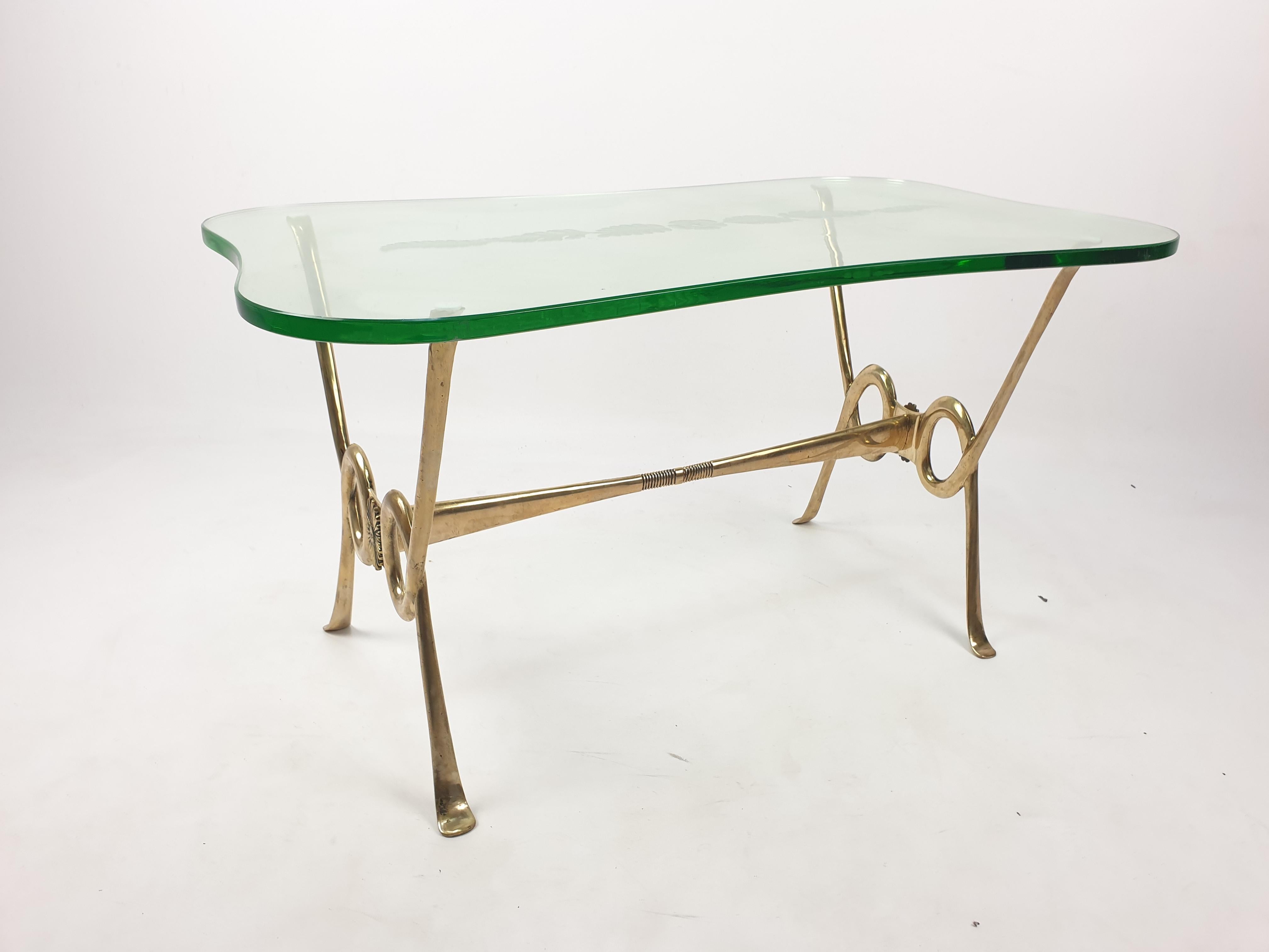 Beautiful and very particular coffee table made of a brass base and a wonderful etched glass plate. The bright and thick glass is wonderful made with lovely curves. Look at the pictures for the amazing etched flowers. This is a stunning piece!
