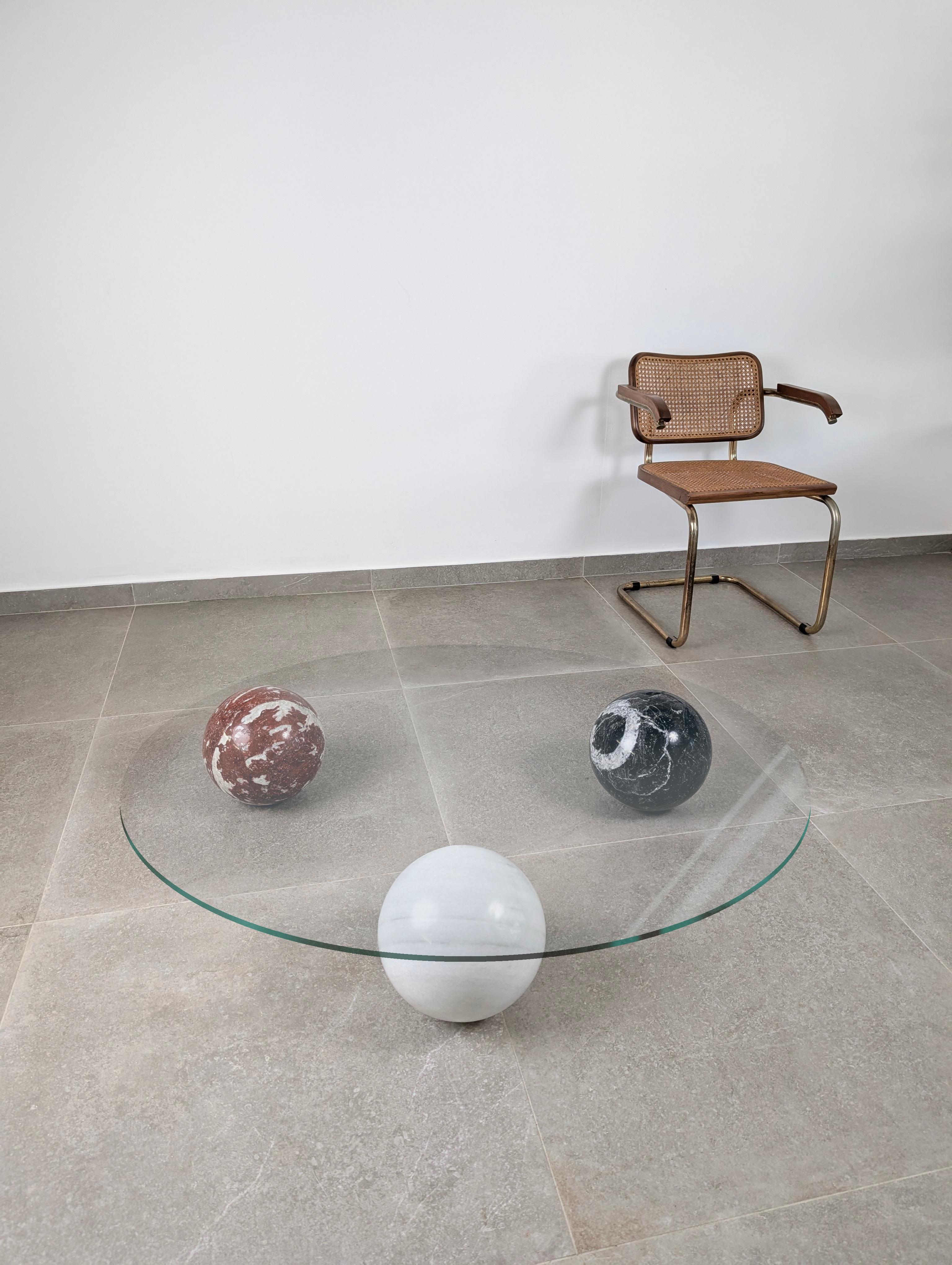 Mesa de centro italiana compuesta por tres esferas de mármol macizo en blanco, negro y rojo. Esta pieza encarna una síntesis perfecta de escultura y funcionalidad, con una fuerte presencia visual que recuerda a los diseños de Cattelan Italia y otras