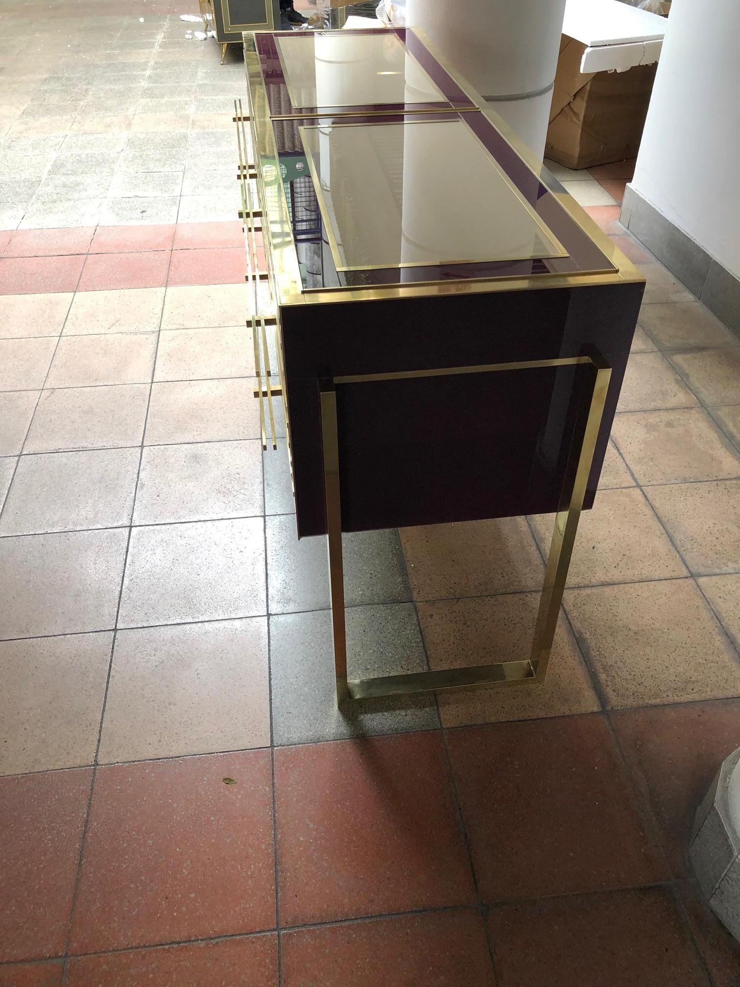 Italian commode in tinted glass and brass with four drawers.