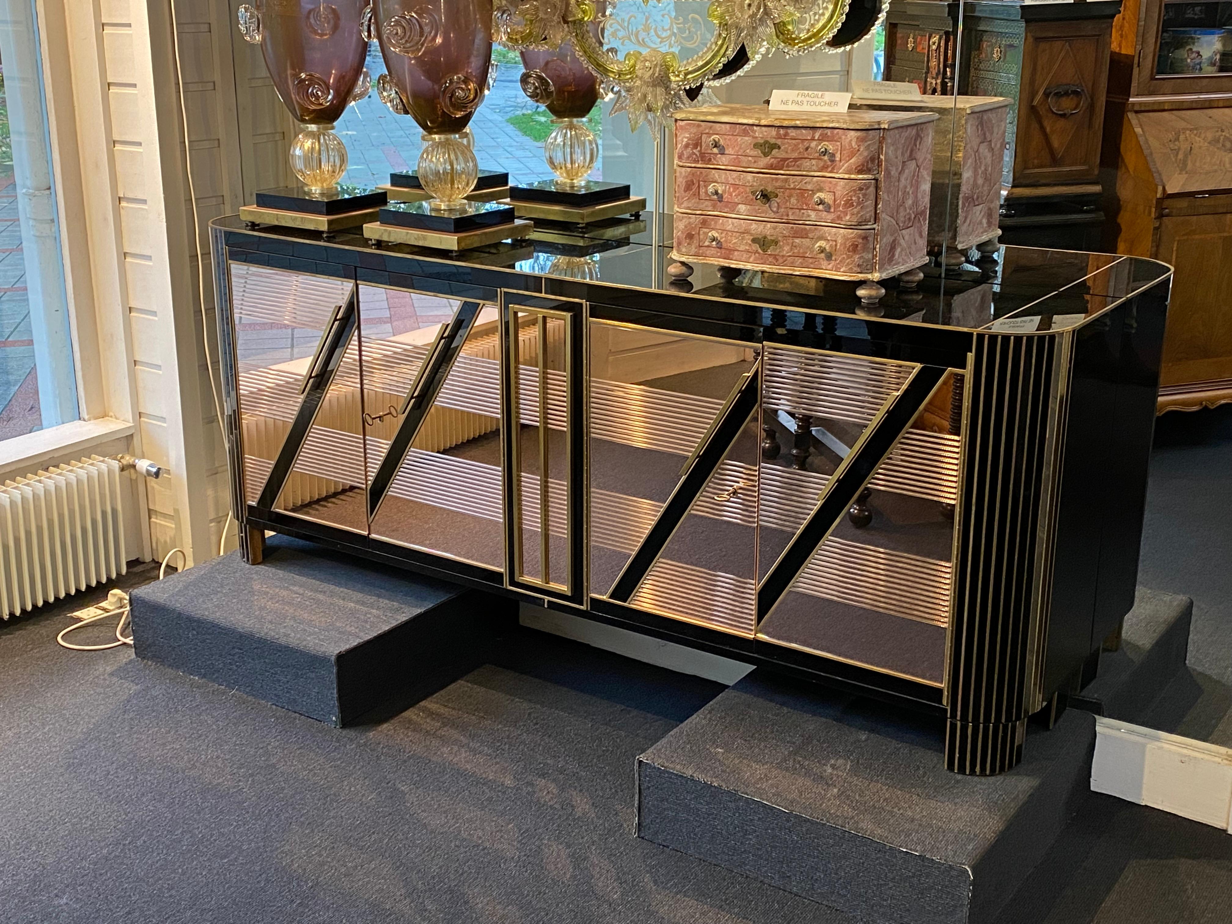 Stylish vintage Italian commode made of Murano tinted glass and brass inserts.
Very elegant in this combination of black and bronze colors.

The chest of drawers is based on a vintage wooden frame, partially covered with black fabric on the inside
