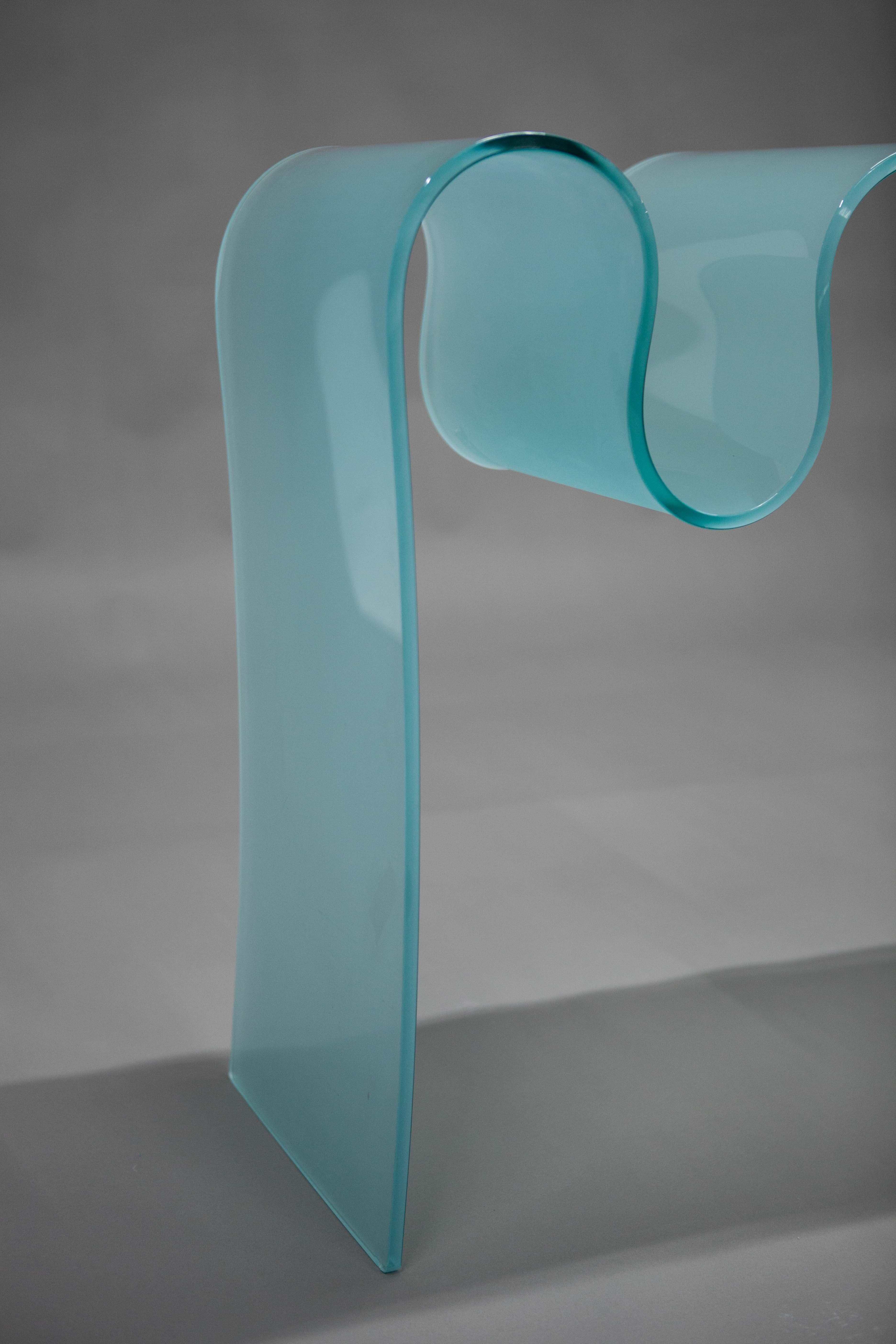 The nineties were characterized by an abundance of endless curvy lines. In this particular instance, the curvy line forms the beautiful silhouette of a wavy glass console. It is not merely aesthetic; rather, the undulating shape simultaneously