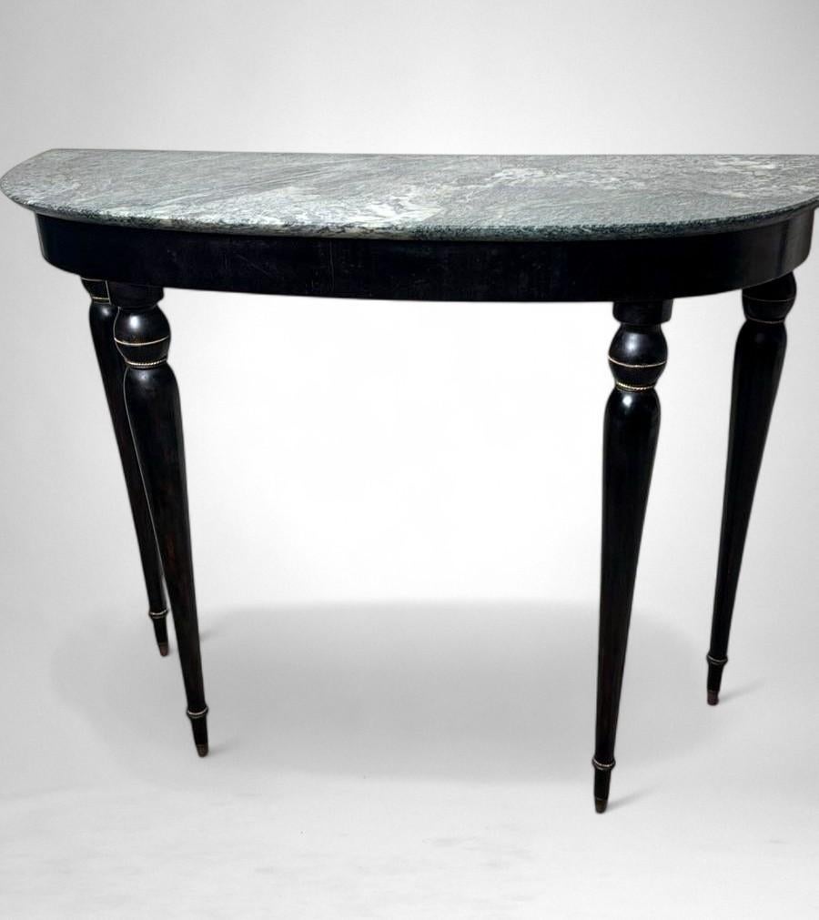 Elegant Italian console table from the 1950s, crafted from solid wood with an ebonized finish and featuring a fine “Verde Alpi” marble top. The demilune profile of the top, combined with four tapered legs, lends the piece a sense of lightness and