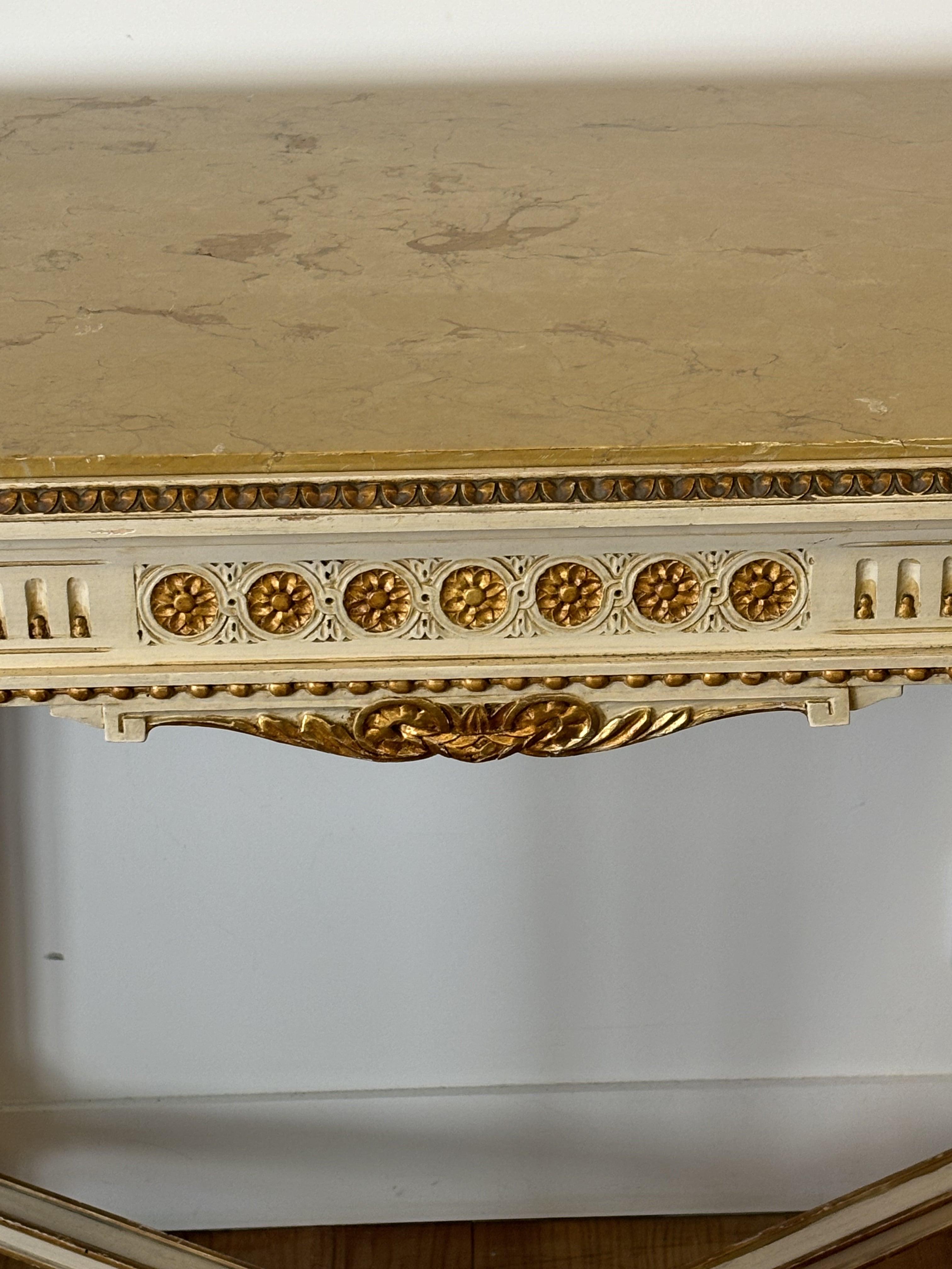 Beautiful Italian neoclassical console table from Napoli, mid-20th century with four legs, in cream and gold lacquered wood, belt decorated with rosettes, square legs, the legs are tapered and fluted. Entretoise topped with a top, cream marble top.