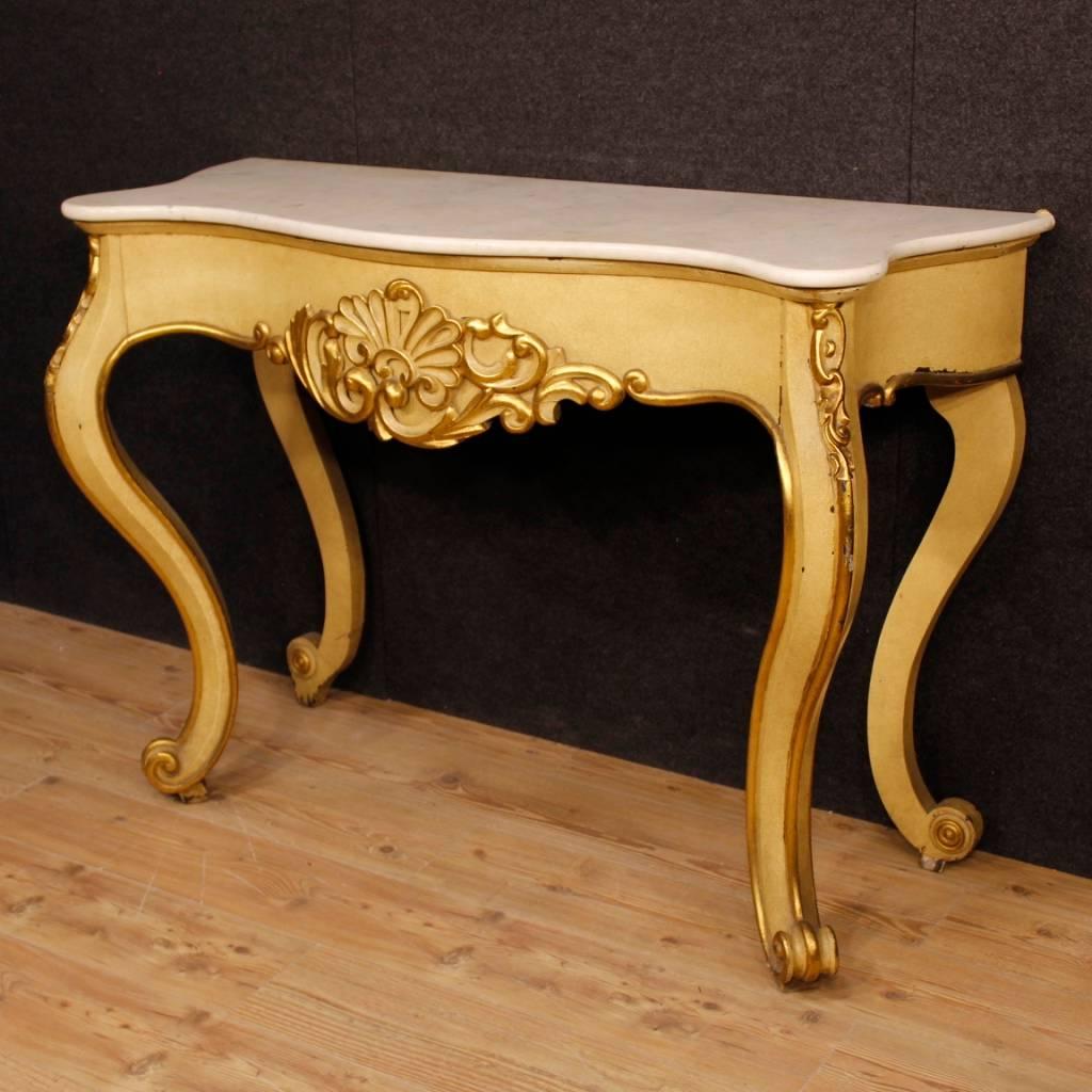 Italian console table from the mid-20th century. Sculptured, lacquered and gilded wooden furniture of beautiful decoration. Console with four legs of good solidity finished with curl feet. Furniture equipped with original marble top of good measure