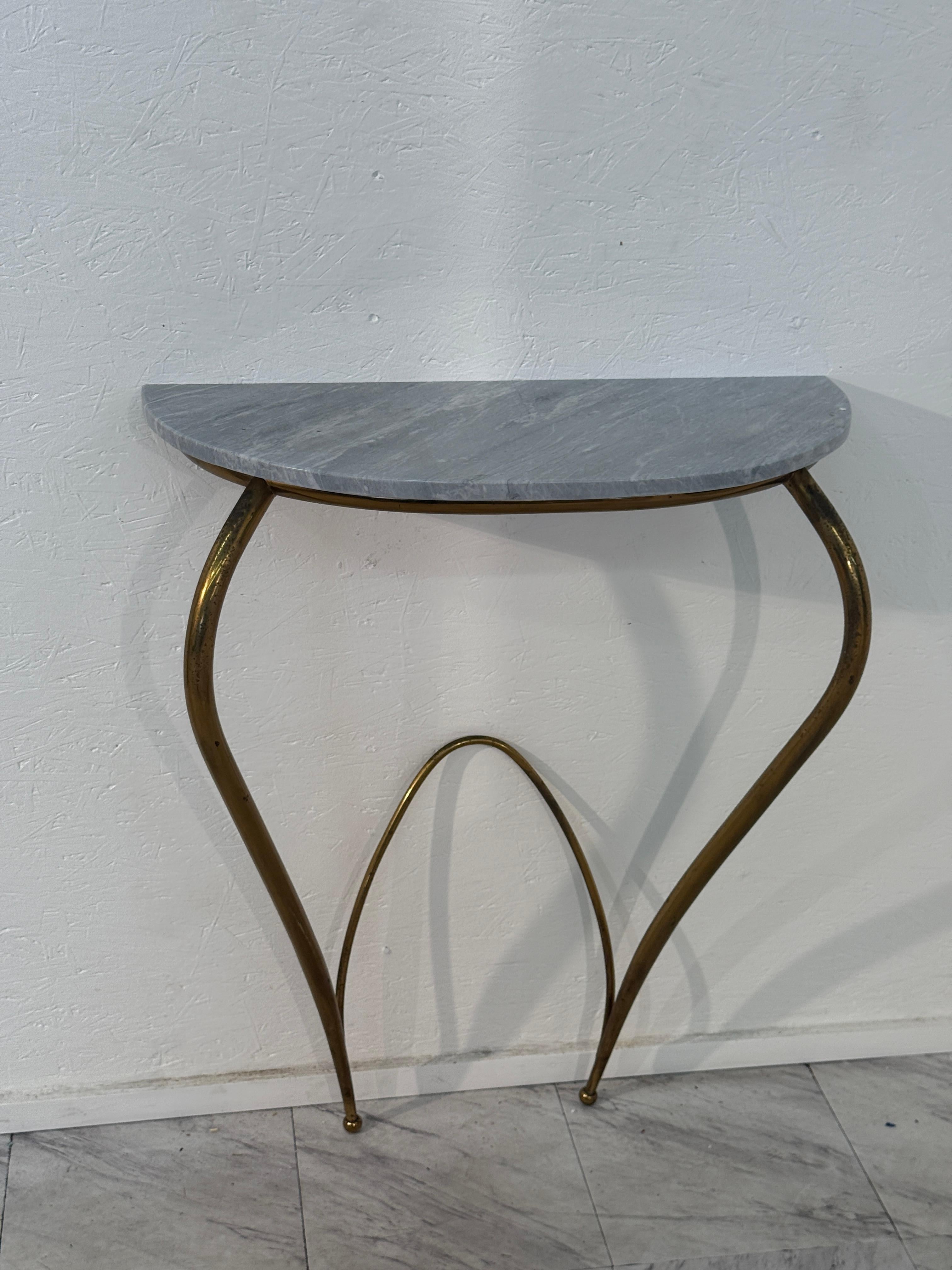 A refined Italian mid-century console table featuring a smooth gray marble top with subtle veining, set upon an elegantly curved brass base. The sculptural legs, with their fluid and organic form, create a striking visual balance between lightness