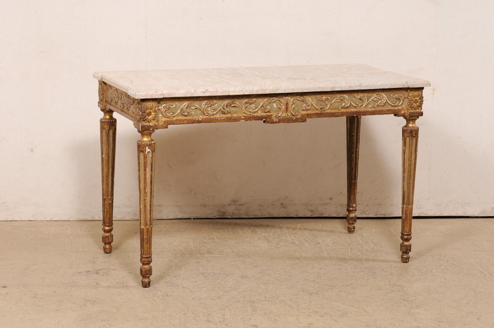 An Italian carved and giltwood console table, with its original marble top, from the turn of the 19th and 20th century. This antique table from Italy has a rectangular-shaped marble top with projected squared corners, atop an apron carved with