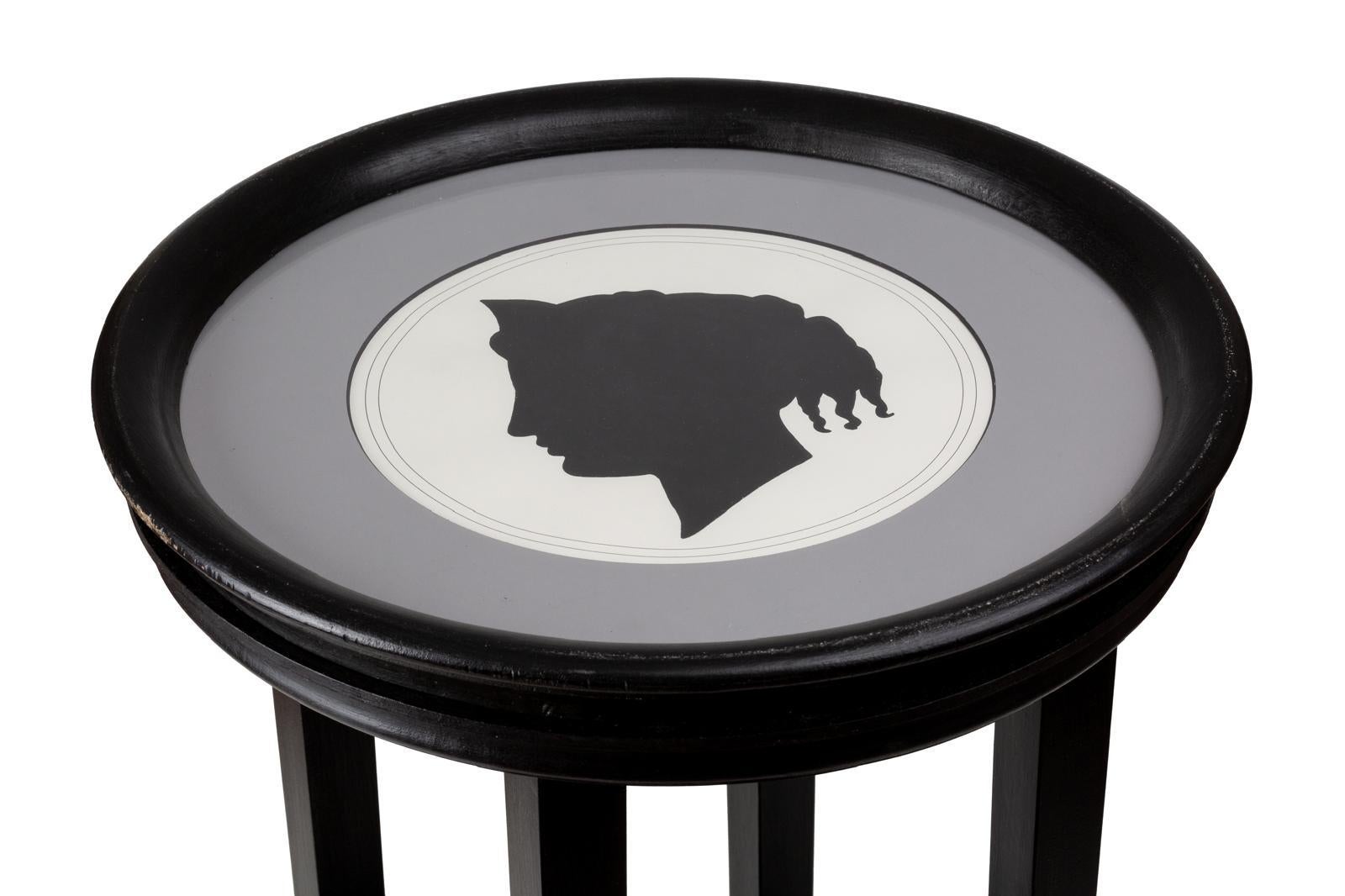 One of two beautiful side table with a neoclasssical woman silhouette black profile print with white background, framed by  a delicate grey passpartout and a round black frame with glass. 
This coffee table fits well in any space and type of