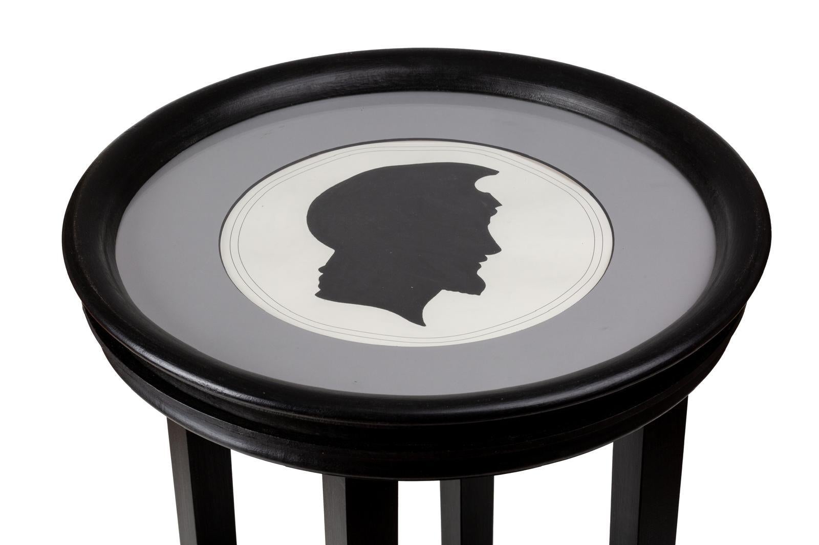 One of two beautiful side table with a neoclasssical man silhouette black profile print with white background, framed by  a delicate grey passpartout and a round black frame with glass. 
This coffee table fits well in any space and type of furniture