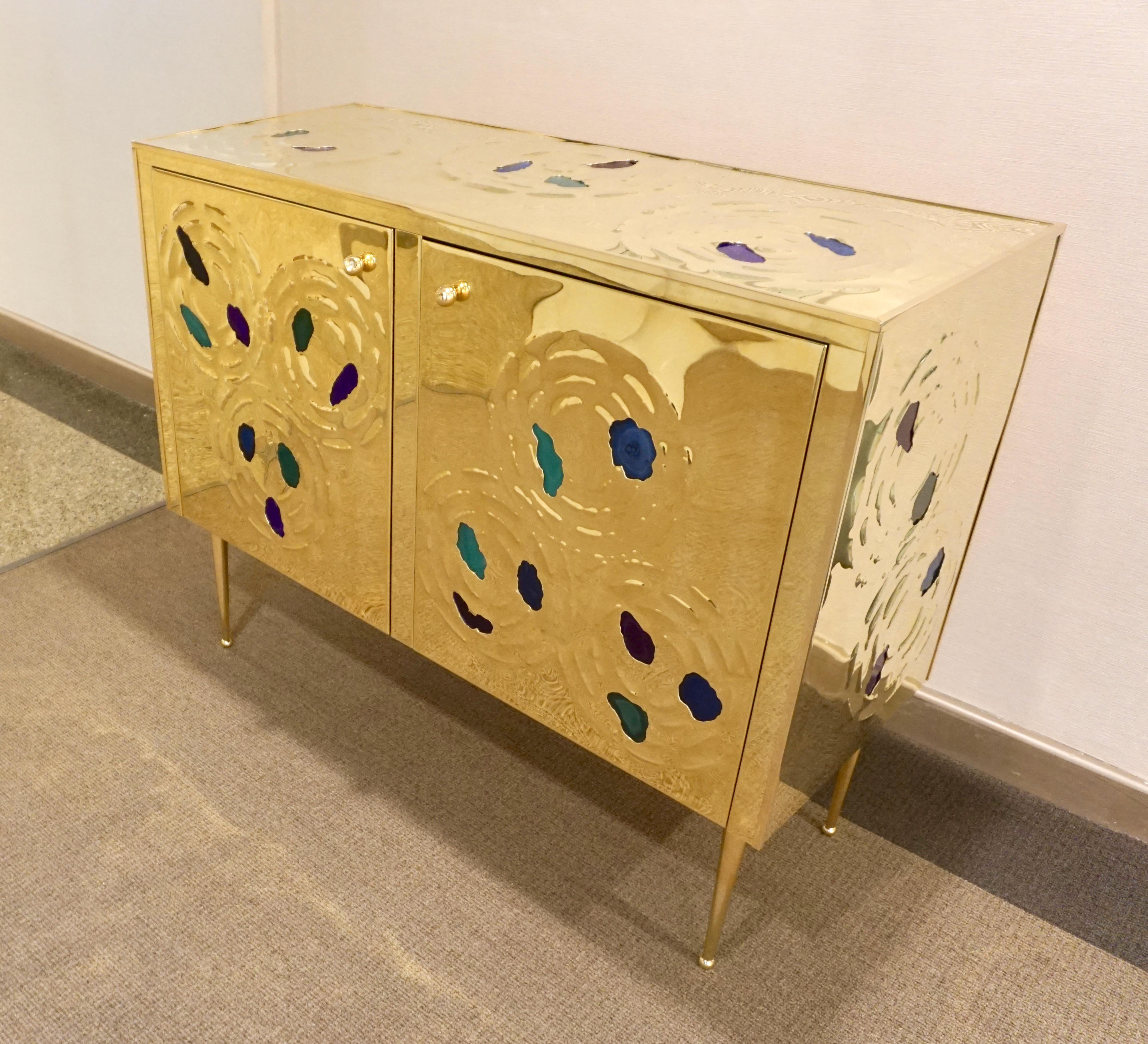 A fine design Italian credenza or sideboard with two doors, entirely handmade, wrapped in natural brass decorated with insets of cut agate in purple, blue and green. The stone is set like jewelry in the brass surround hammered with a sophisticated