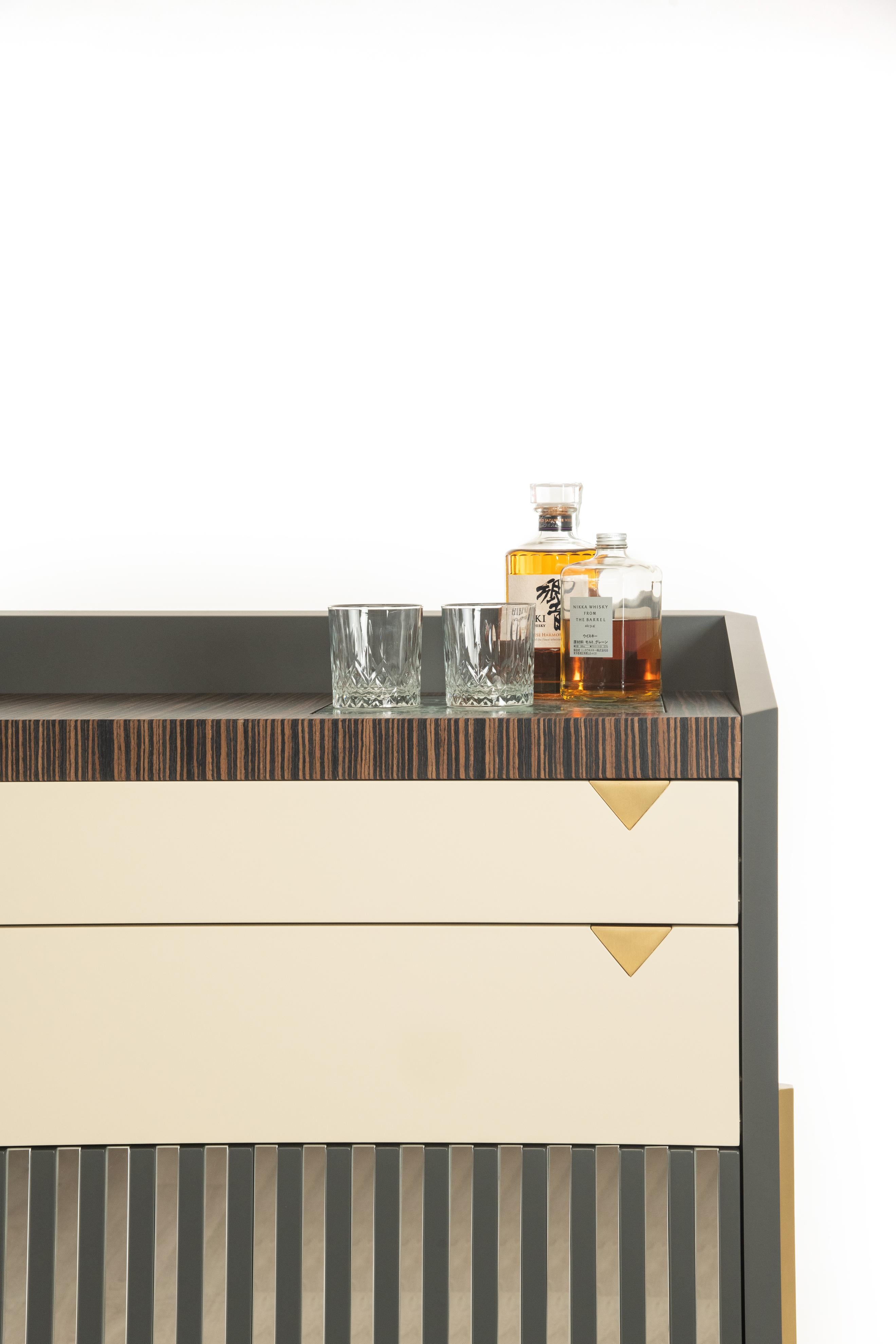El armazón de este mueble de diseño es de madera lacada mate apoyada en las sólidas patas de latón satinado de sección hexagonal. También hay una encimera de mármol 