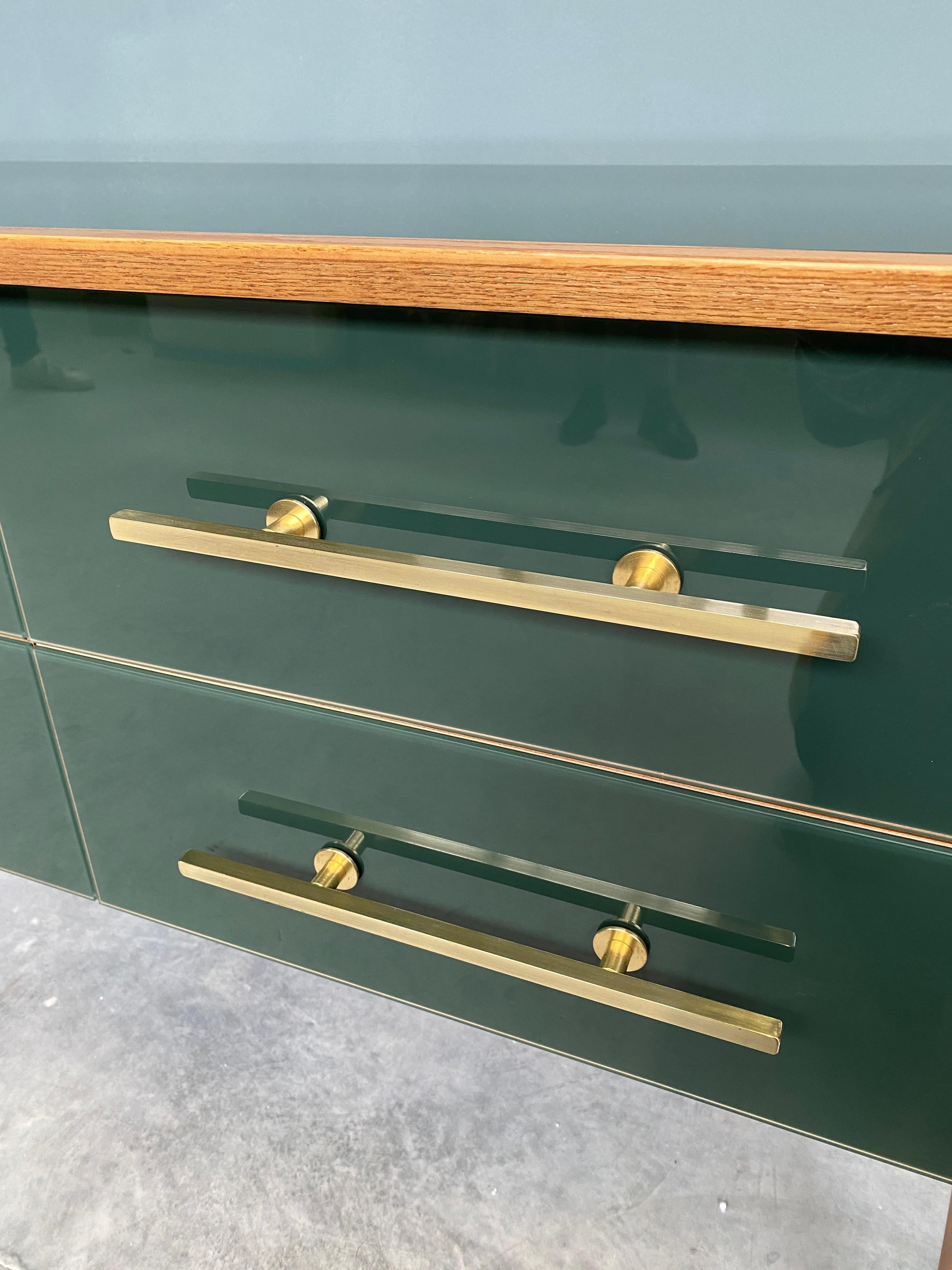 Beautiful dresser designed and handcrafted by us with structure and interior in solid wood, legs and finishes in brass and tops and decorations in emerald colored Murano glass. 
It is an object of high quality and refinement, ideal for giving