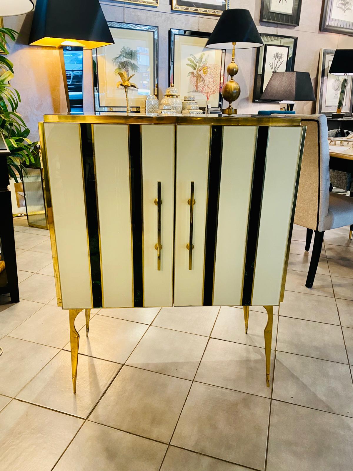 Beautiful sideboard designed and handcrafted by us with structure and interior in solid wood, molded legs and finishes in brass and tops and decorations in greenand white colored Murano glass. The top is totally green. The vertical parts are white