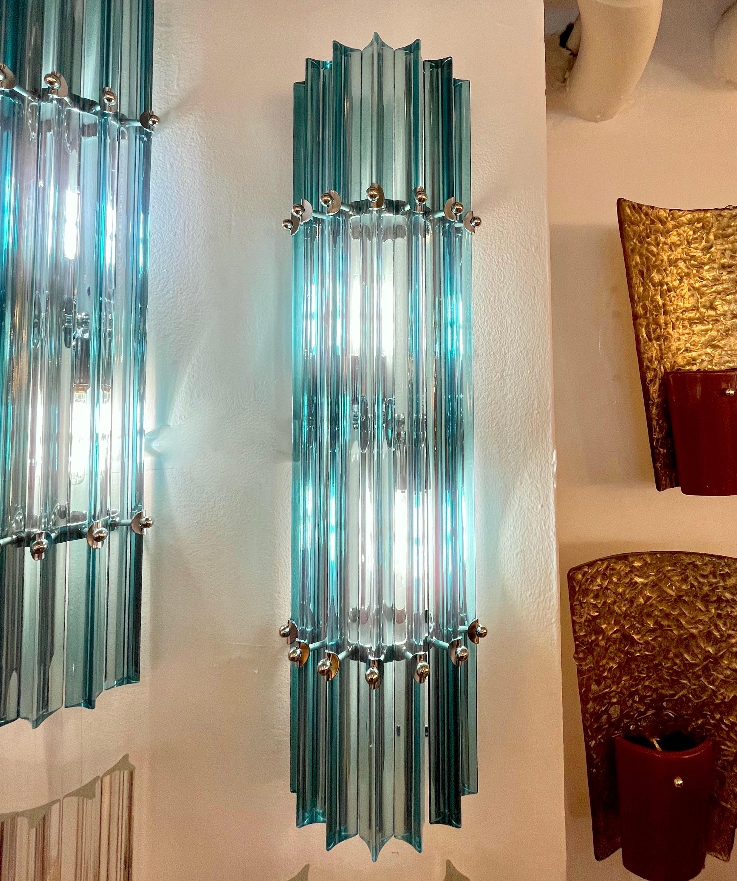 Very sleek custom Venetian pair of glass wall lights with organic modern design, consisting of seven straight aqua blue Murano glass rods of triangular section with attractive concave sides, that not only highlight the curved design but amplify the