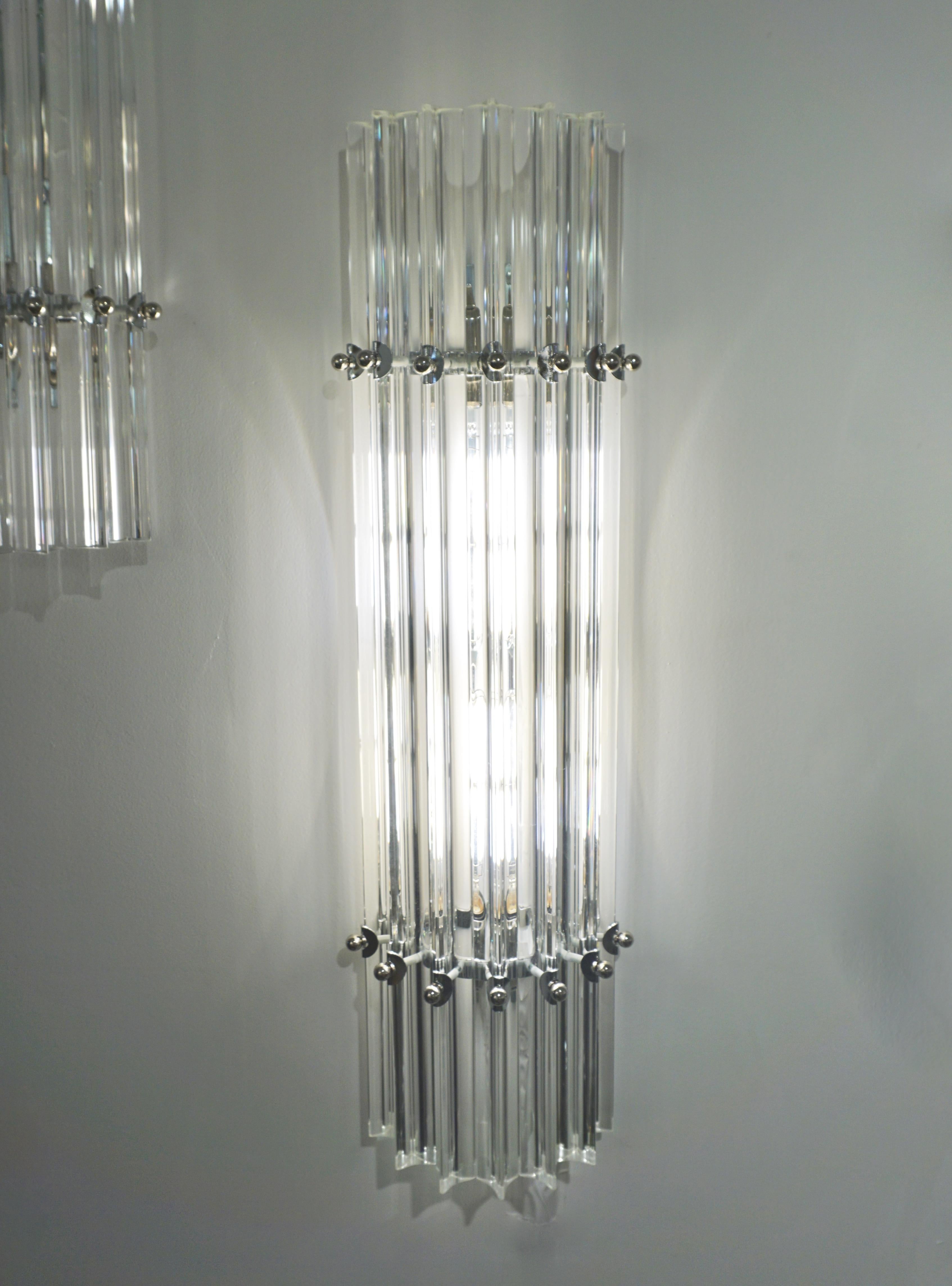 Very sleek custom Venetian pair of wall lights with organic minimalist design, consisting of seven straight crystal clear Murano glass rods of triangular section with amazing concave sides, that not only highlight the curved design but amplify the
