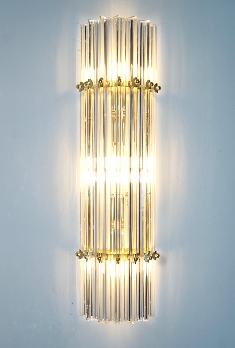 Very sleek custom Venetian pair of crystal wall lights with organic modern design, consisting of seven straight crystal clear Murano glass rods of triangular section with attractive concave sides, that not only highlight the curved design but