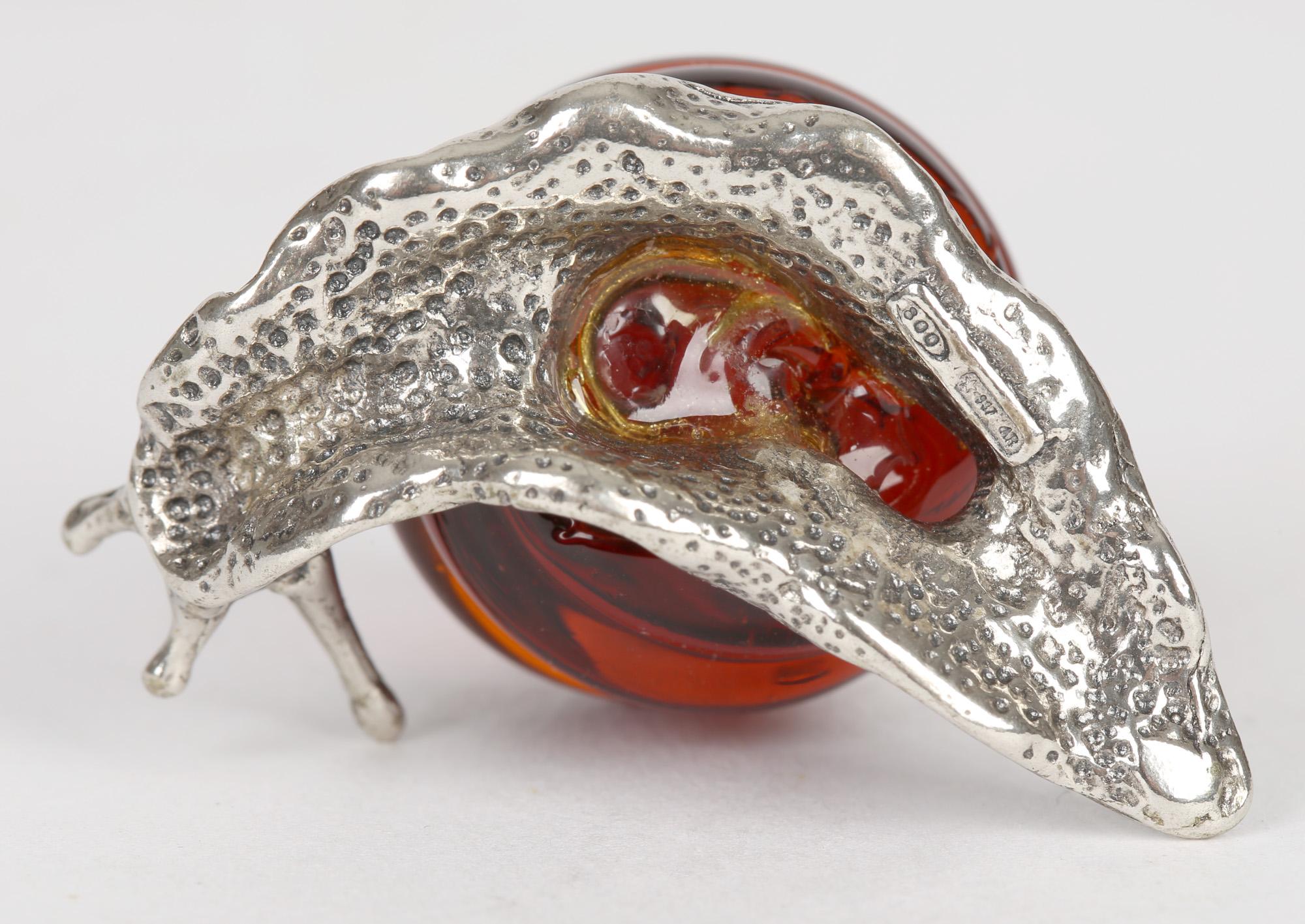 A delightful contemporary Italian silver snail mounted with a Murano amber glass shell dating from the latter 20th century. The body is made from silver with good detail with a glass coiled shell attached to its back. The snail does not have a