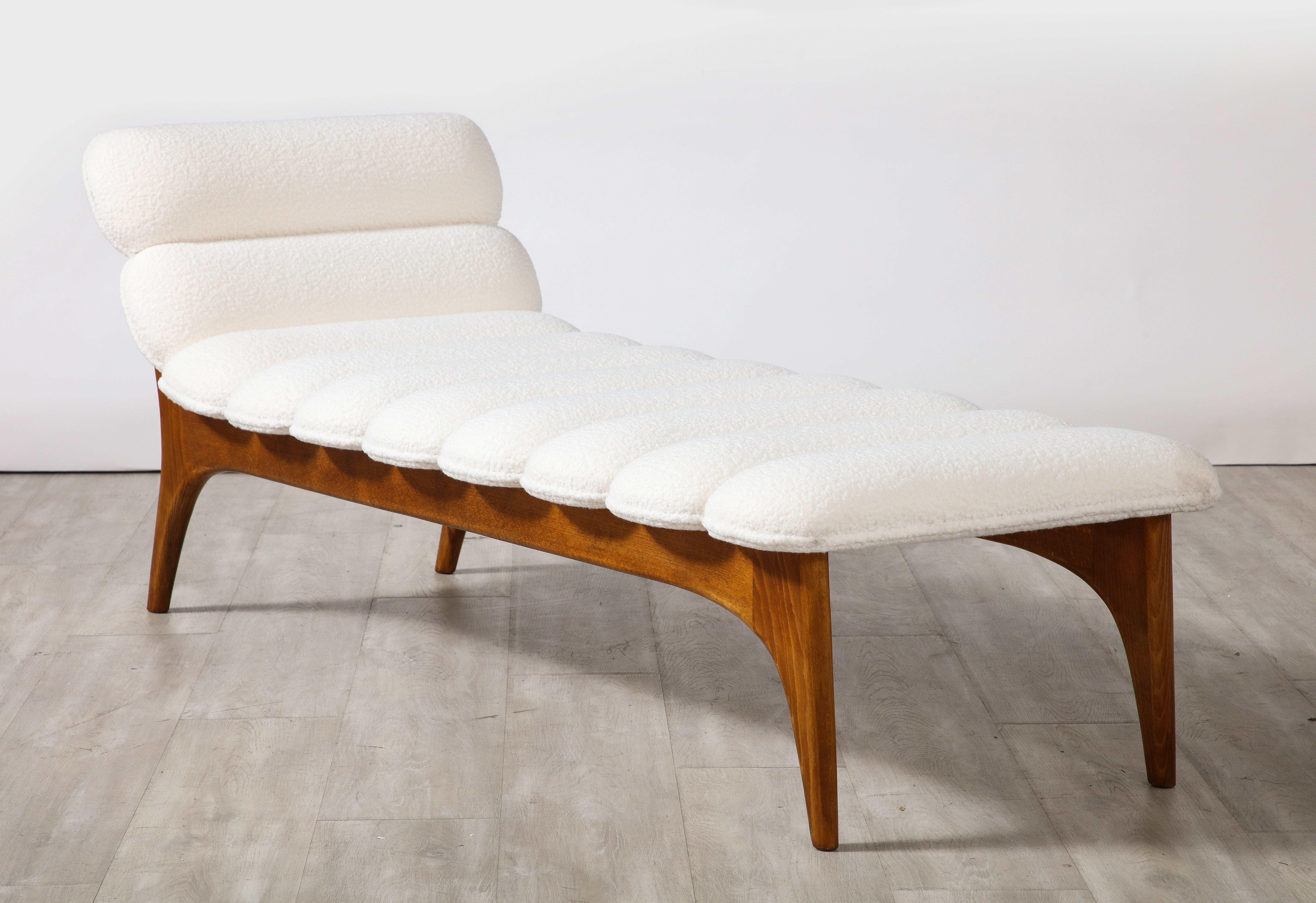 Italian contemporary walnut and channel tufted chaise longue or daybed with headrest. The whole with channel tufting in a rich creamy Italian bouclette. Highly sculptural and elegant with splayed legs. A striking and classic addition to any interior