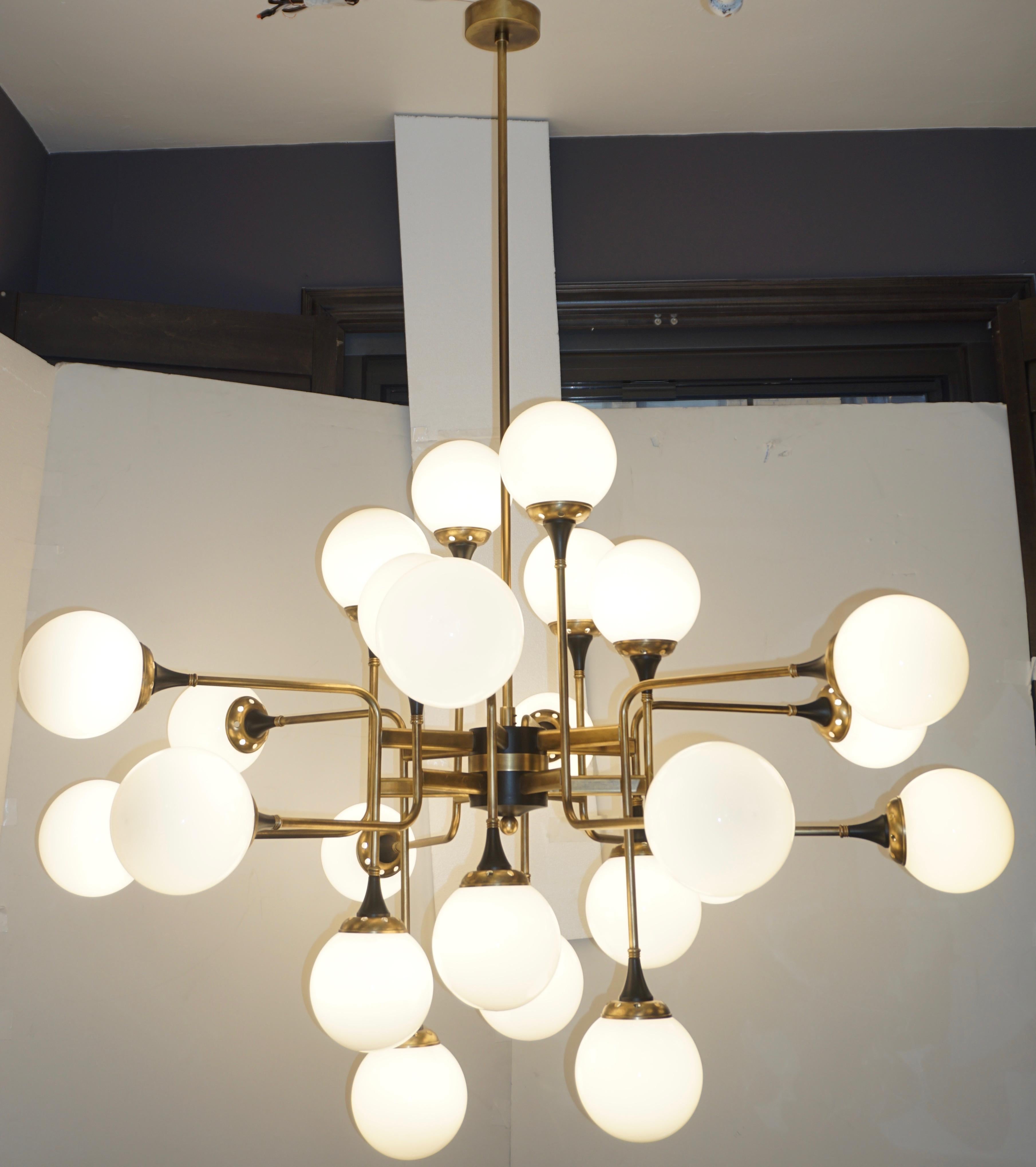 Contemporary custom made chandelier of grand scale and mid-century modern geometric design with a Sputnik inspiration, entirely handcrafted in Italy. The brass structure with a vintage finish is composed of 12 asymmetric bent arms to support 24