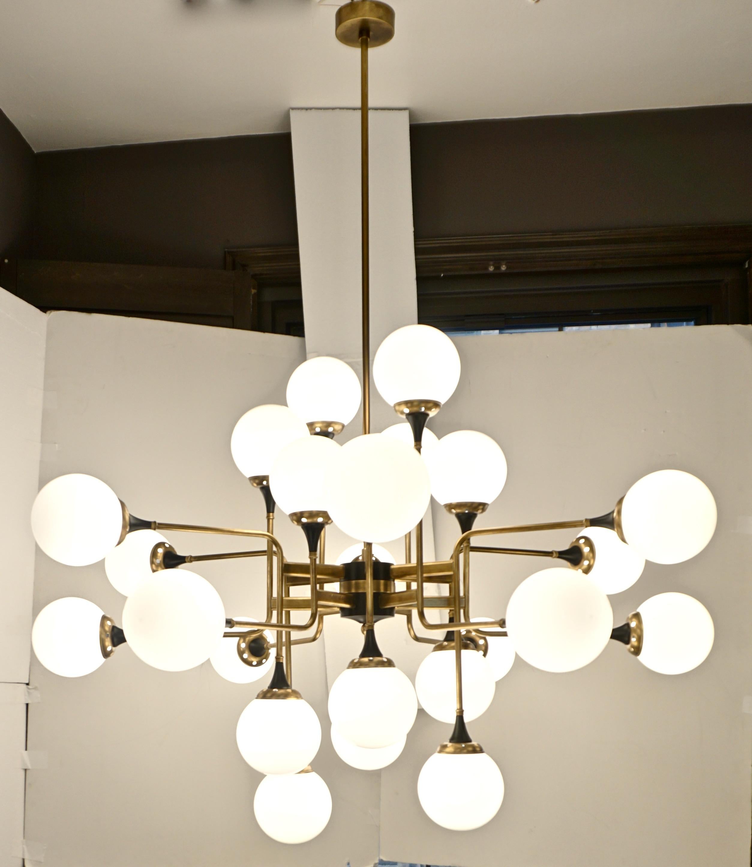 Contemporary custom made chandelier of grand scale and Mid-Century Modern geometric design with a Sputnik inspiration, entirely handcrafted in Italy. The brass structure with a vintage finish is composed of 12 asymmetric bent arms to support 24