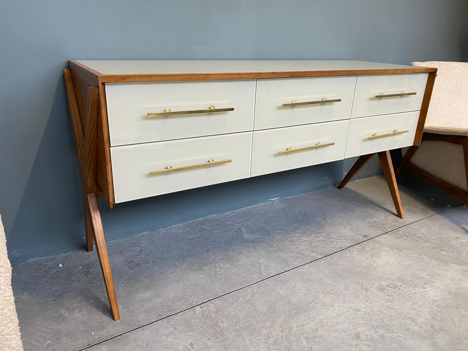 Magnifique commode conçue et fabriquée à la main par nos soins avec structure et intérieur en bois massif, pieds et finitions en laiton et plateaux et décorations en verre de Murano de couleur blanc chaud. 
C'est un objet de grande qualité et de