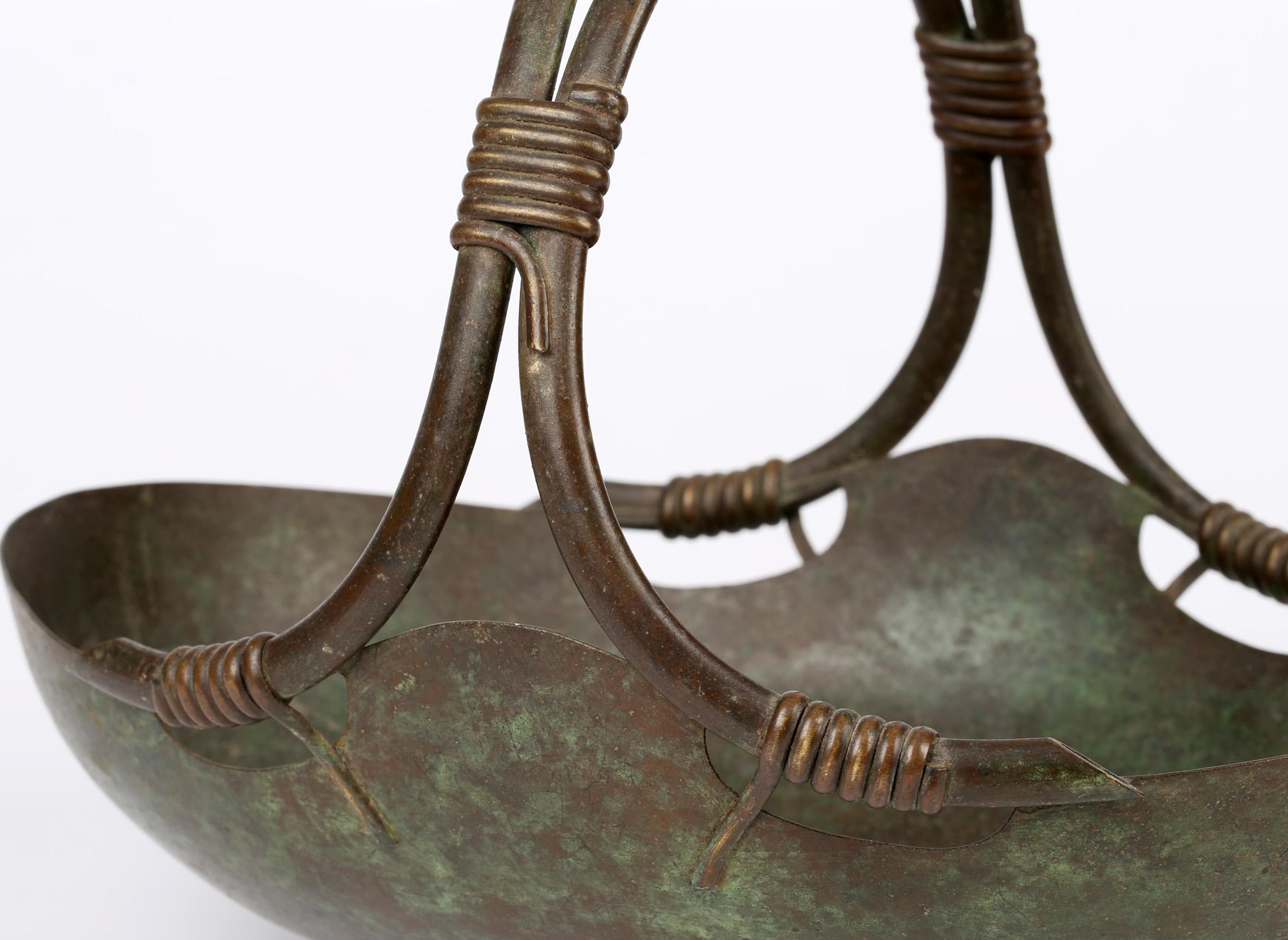 A very stylish Continental, probably Italian, vintage Art Deco bronze basket shaped fruit bowl dating between 1920 and 1950. The bowl of oval shape stands raised on a narrow foot rim and has a twin hollow tubular loop handle with mock coiled wires