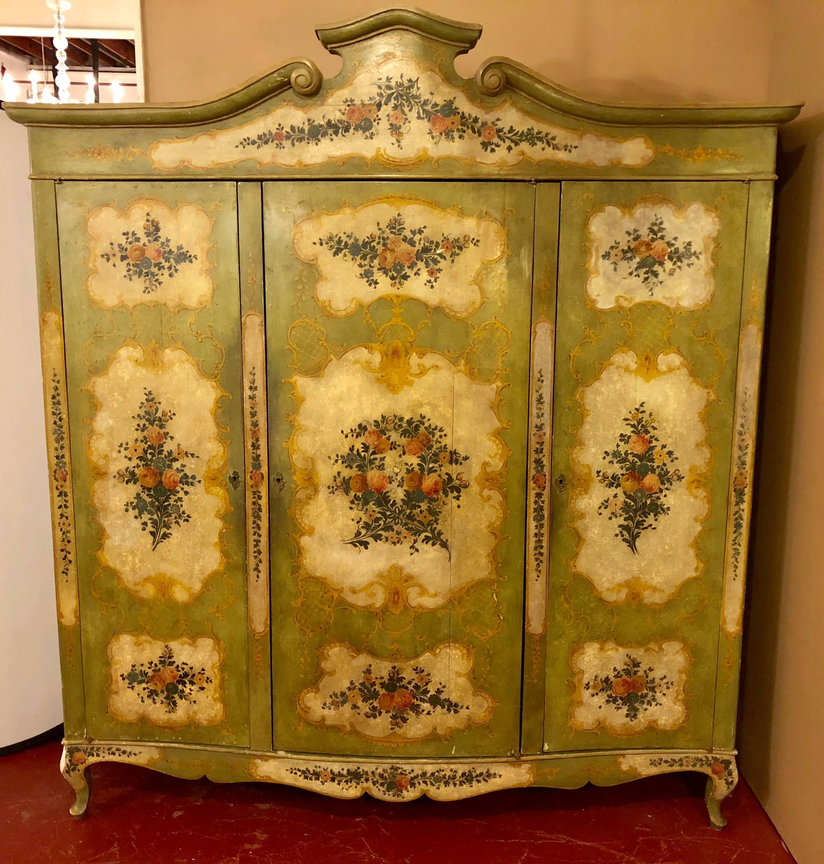 An Italian Continental floral painted wardrobe or armoire chest cabinet. This large three-drawer cabinet is finely hand paint decorated with design of flowers and leafs with vines. The side painted to match the front.