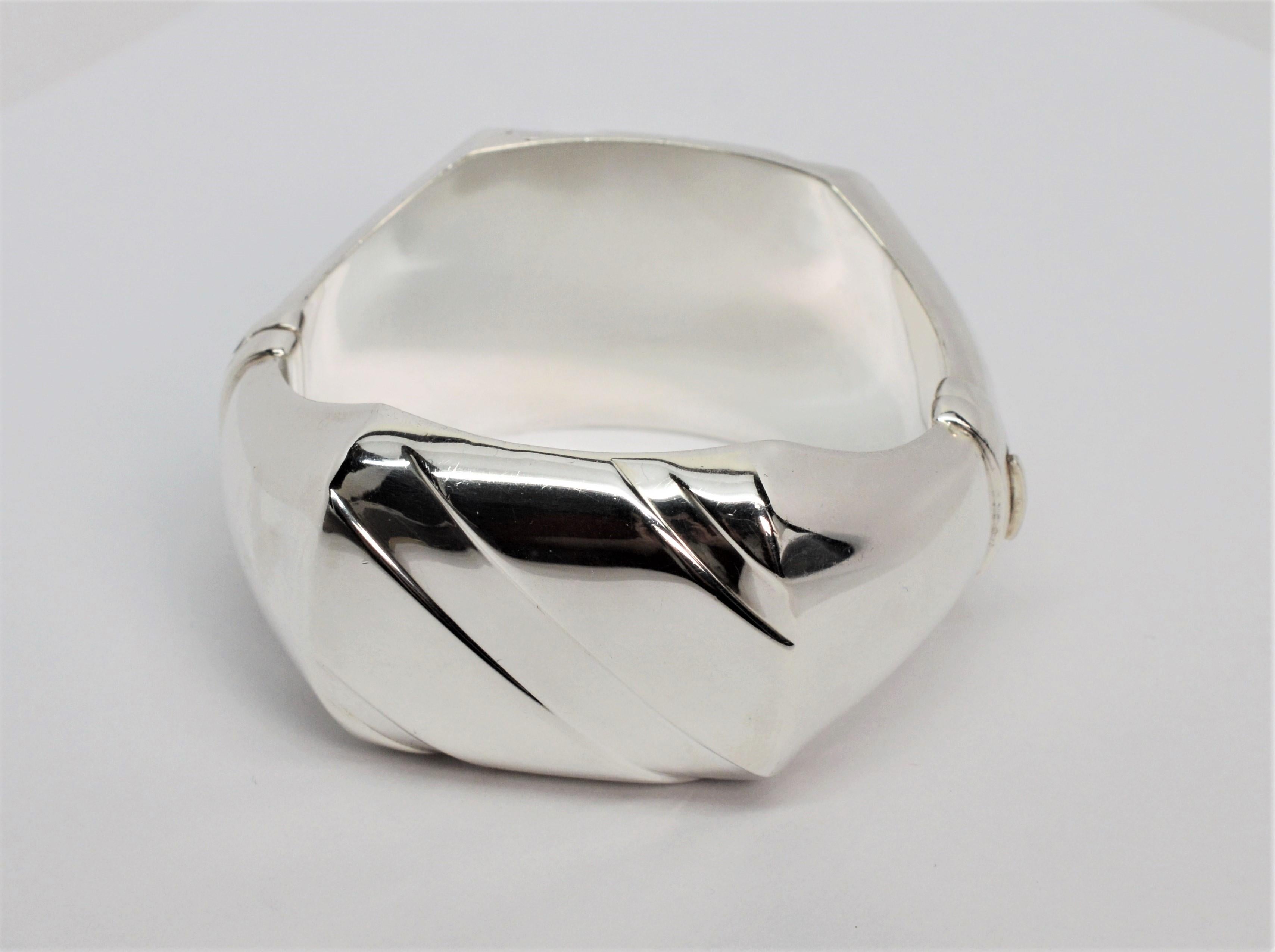 Dieser breite Armreif aus Sterlingsilber mit hochglänzender, spiegelnder Oberfläche hat einen kühnen, modernen Look. Das Kleidungsstück umspielt das Handgelenk und ist vorne und hinten mit asymmetrischen Linien verziert. Alle sind aus Sterlingsilber