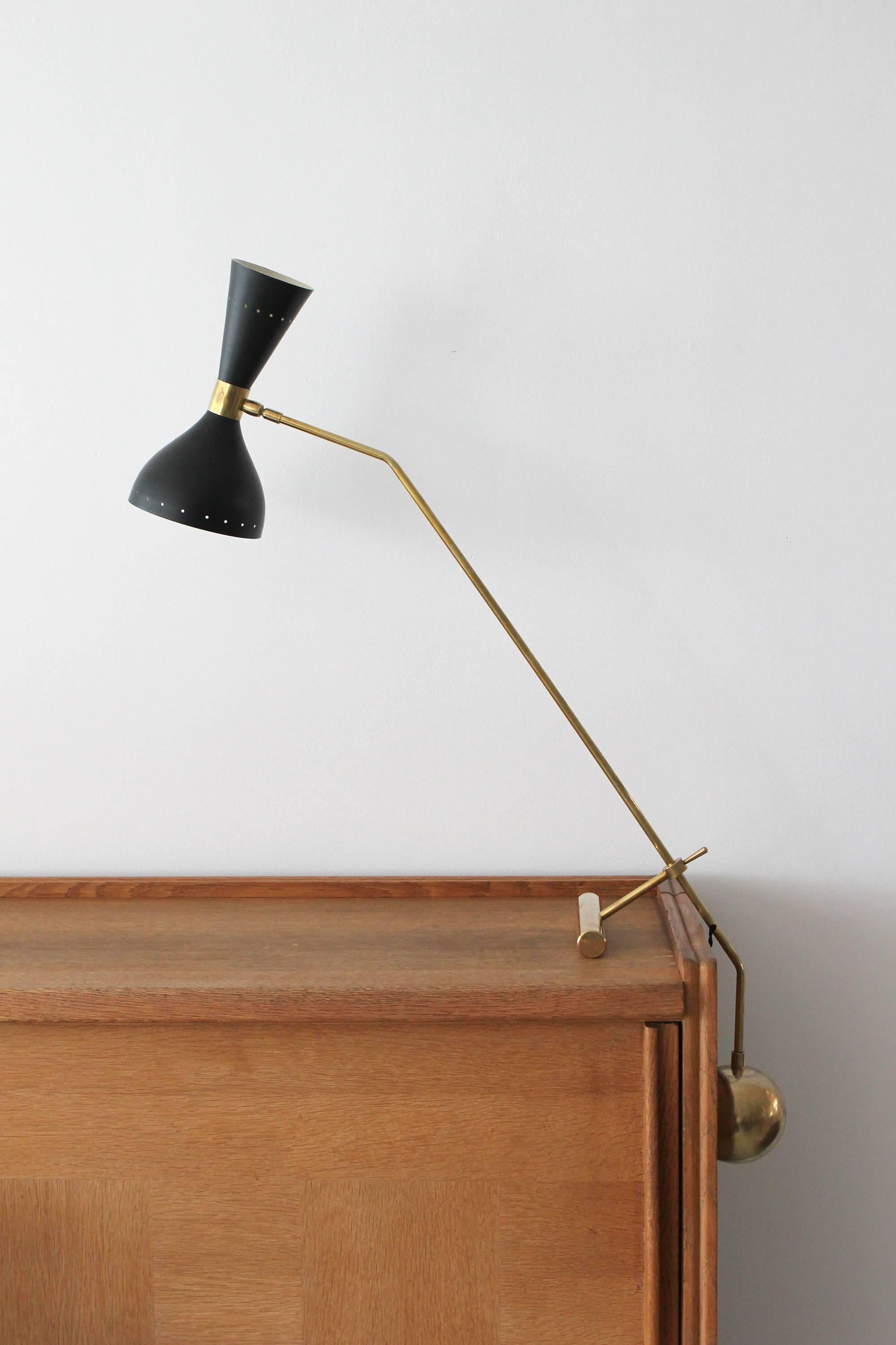 Italian desk lamp with heavy brass counterbalance weight, black cone shade that lights up and down.