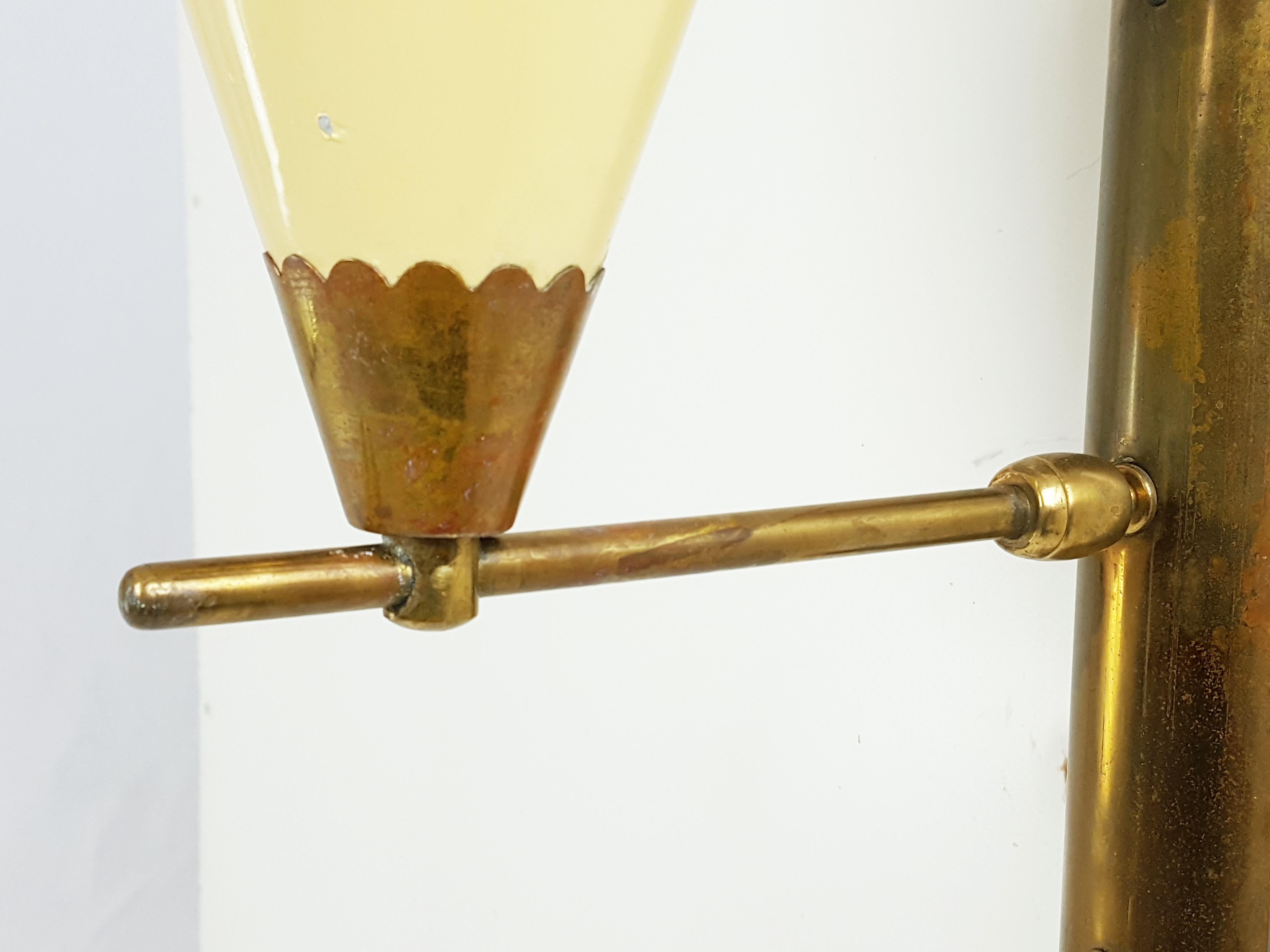 This wall lamp was produced in Italy in the 1950s. It is made from brass and painted aluminum. Adjustable position. the lamp is original in all its parts, but shows visible signs of oxidation and color loss. Sale label still present.