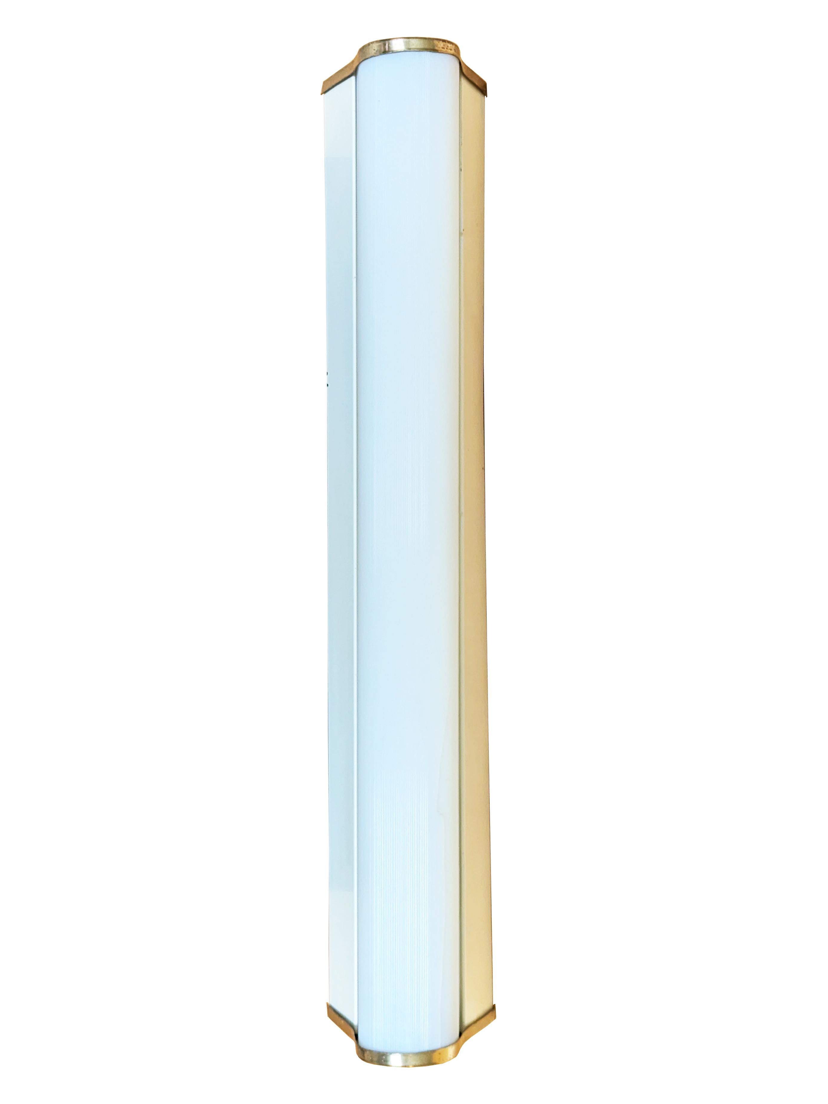 Grande lampada da parete o da soffitto con illuminazione al neon. Struttura in metallo verniciato color crema (alcuni difetti e piccole lacune), coperchi di chiusura laterali in lamiera di ottone. paralume in lamiera di plastica semitrasparente e