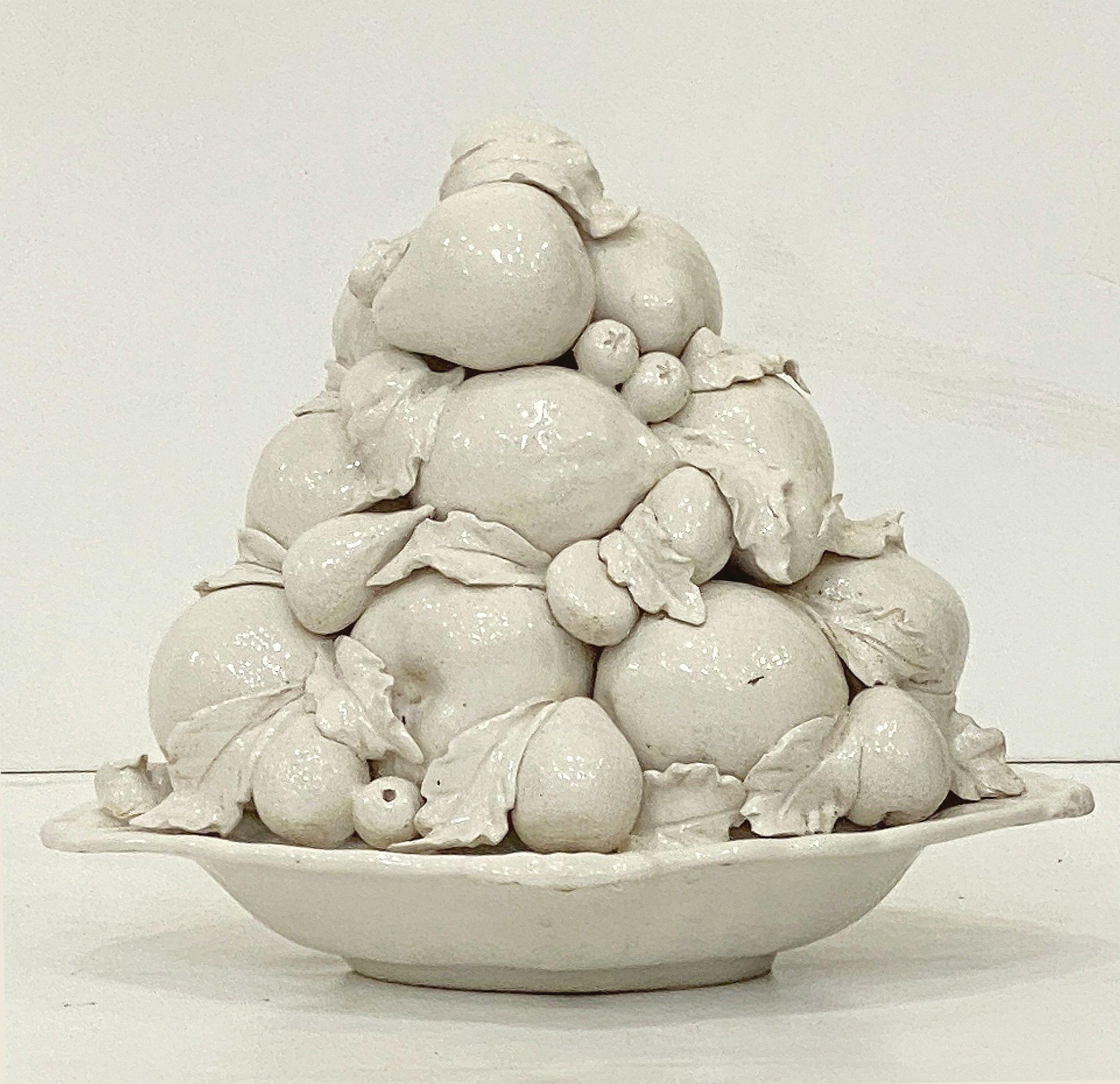 Grande cesto o centrotavola italiano in ceramica smaltata bianca o crema con top topiario di frutta mista, caratterizzato da un rilievo di frutta mista lungo la circonferenza del top su un corpo inferiore a forma di ciotola ovale rialzata.

Misure: