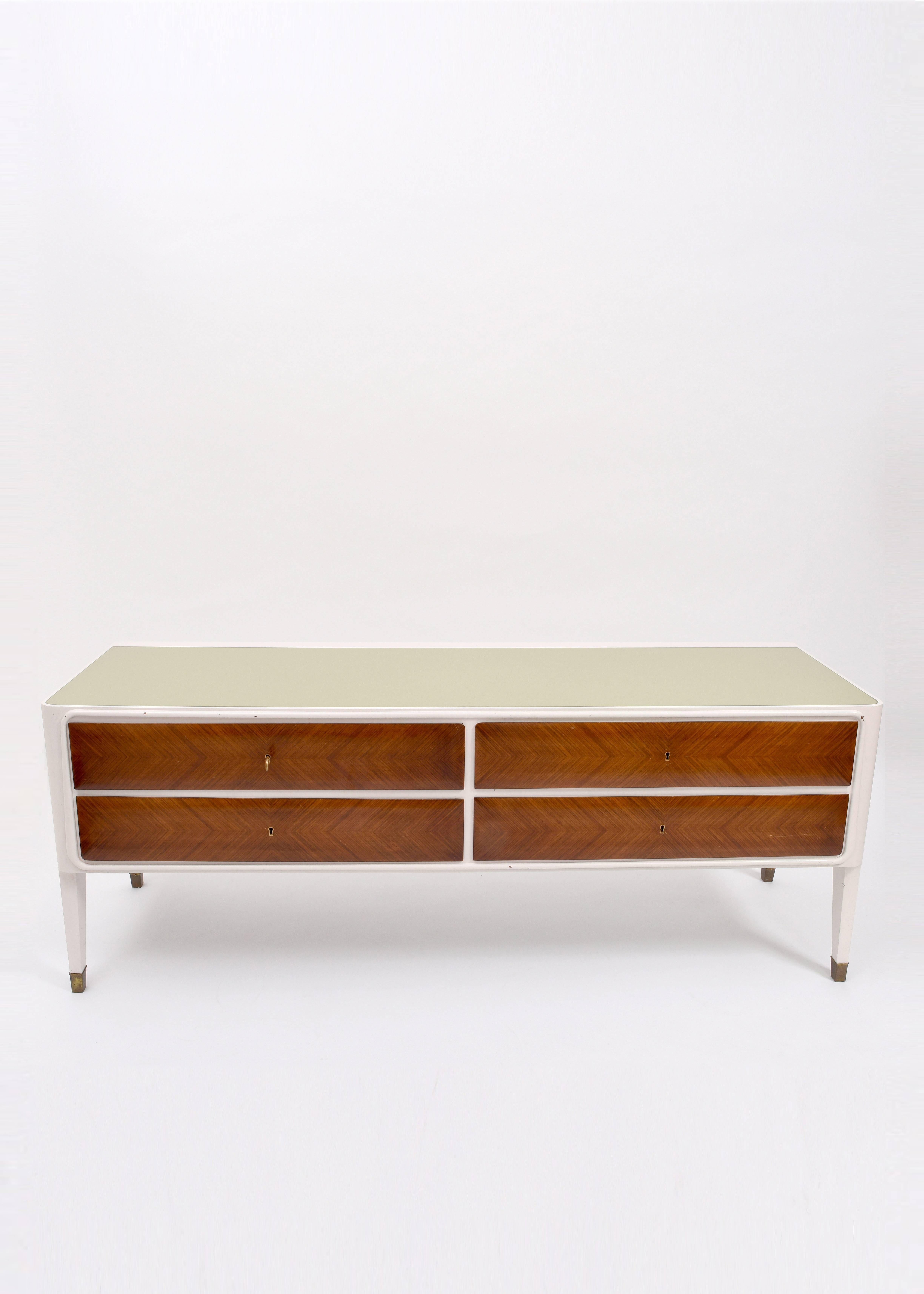 Italian credenza sideboard, circa 1950. White lacquered cabinet with wooden drawers and set-in opaque glass top. Brass feet details, escutcheons and key.