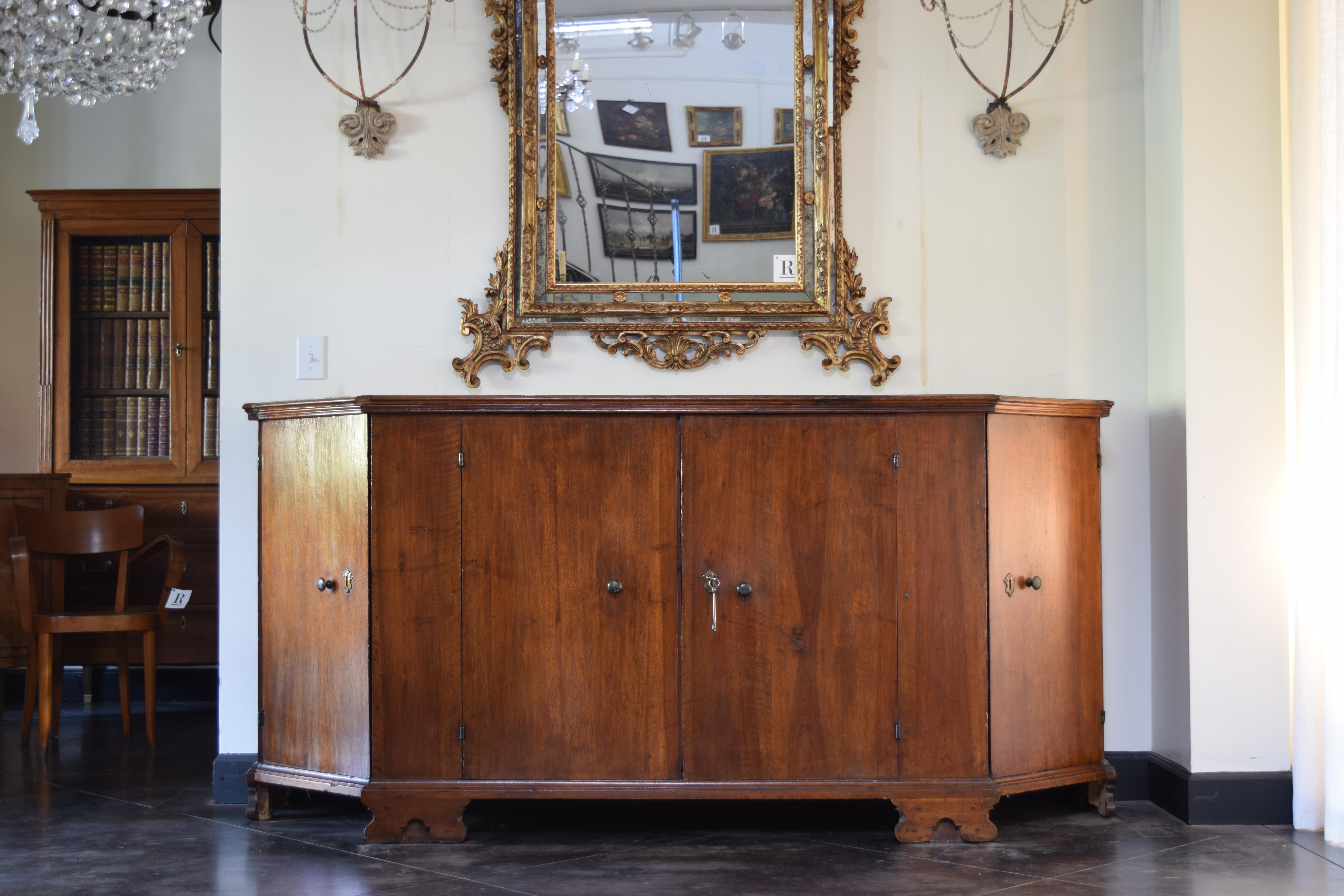 having a rectangular top with canted corners and a molded edge atop a conforming case with 4 drawers and interior shelving, the case raised on shaped bracket feet