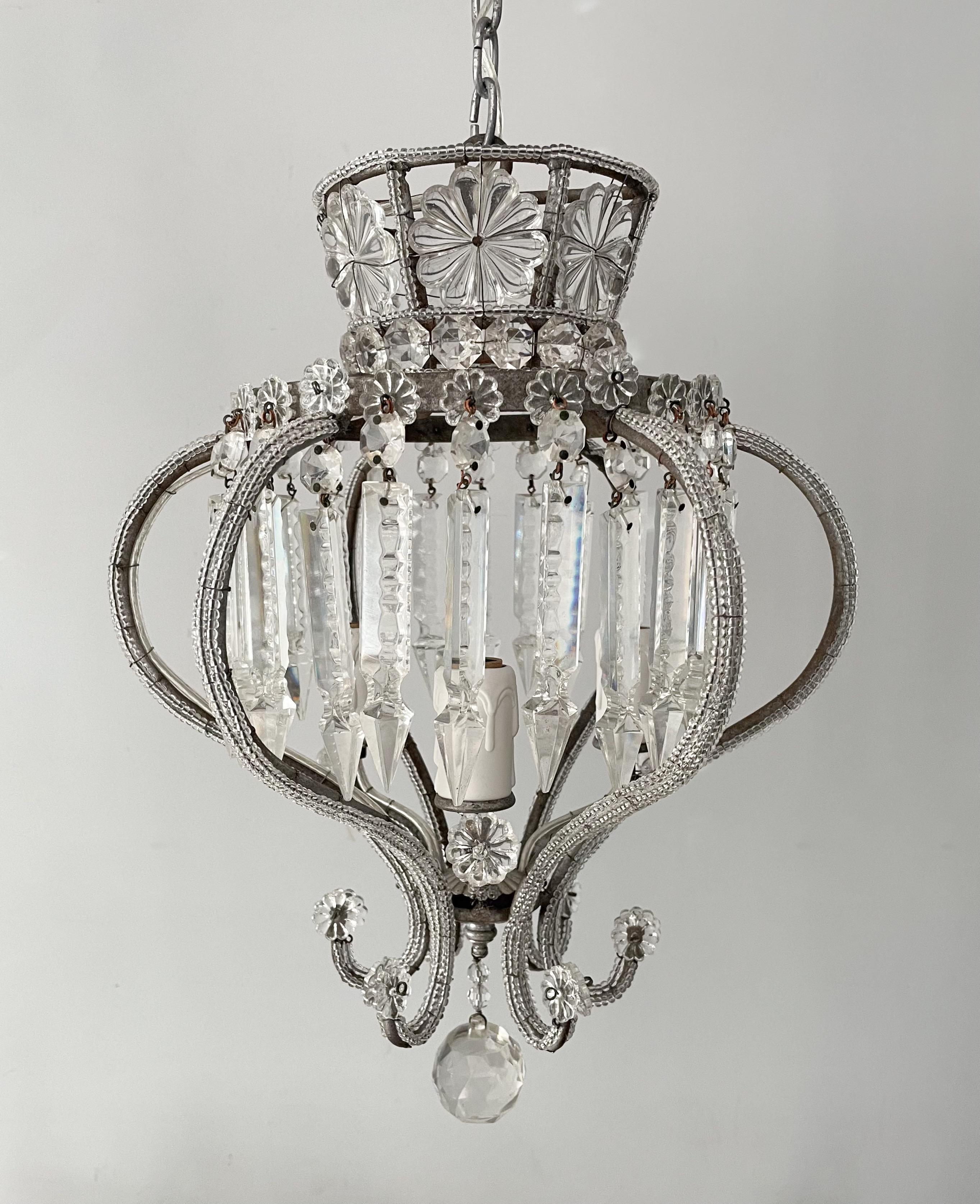 Gorgeous, 1950s Italian crystal beaded chandelier in the neoclassical style.

The chandelier features a silvered-iron, crown shaped frame outlined with glass beads and decorated with large glass rosettes and faceted prisms.

The chandelier is wired
