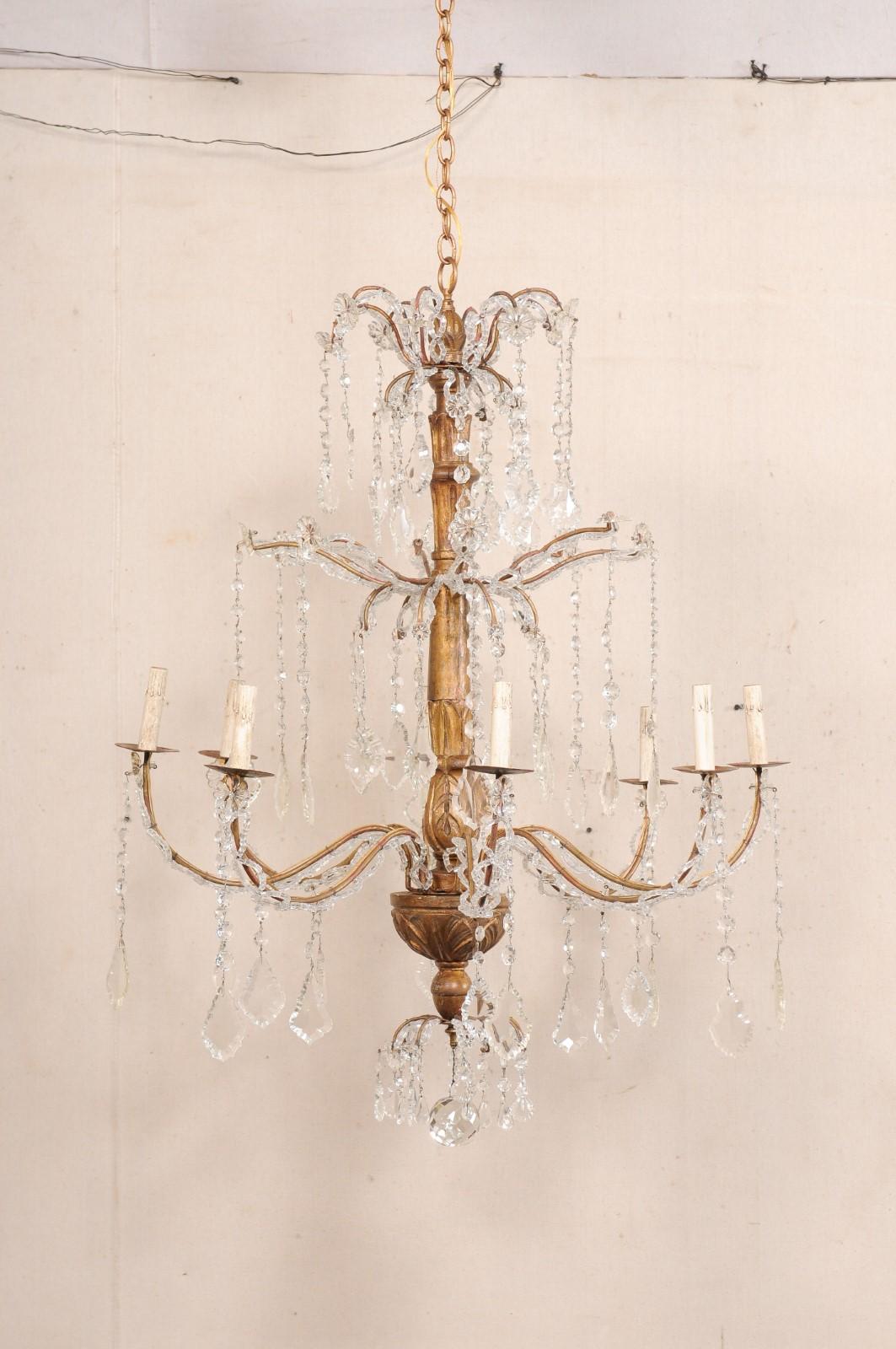 Un lampadario italiano a otto luci in stile colonna in legno con ornamenti in cristallo della metà del XX secolo. Questo lampadario italiano della metà del secolo scorso è caratterizzato da una colonna centrale in legno intagliato con motivo a