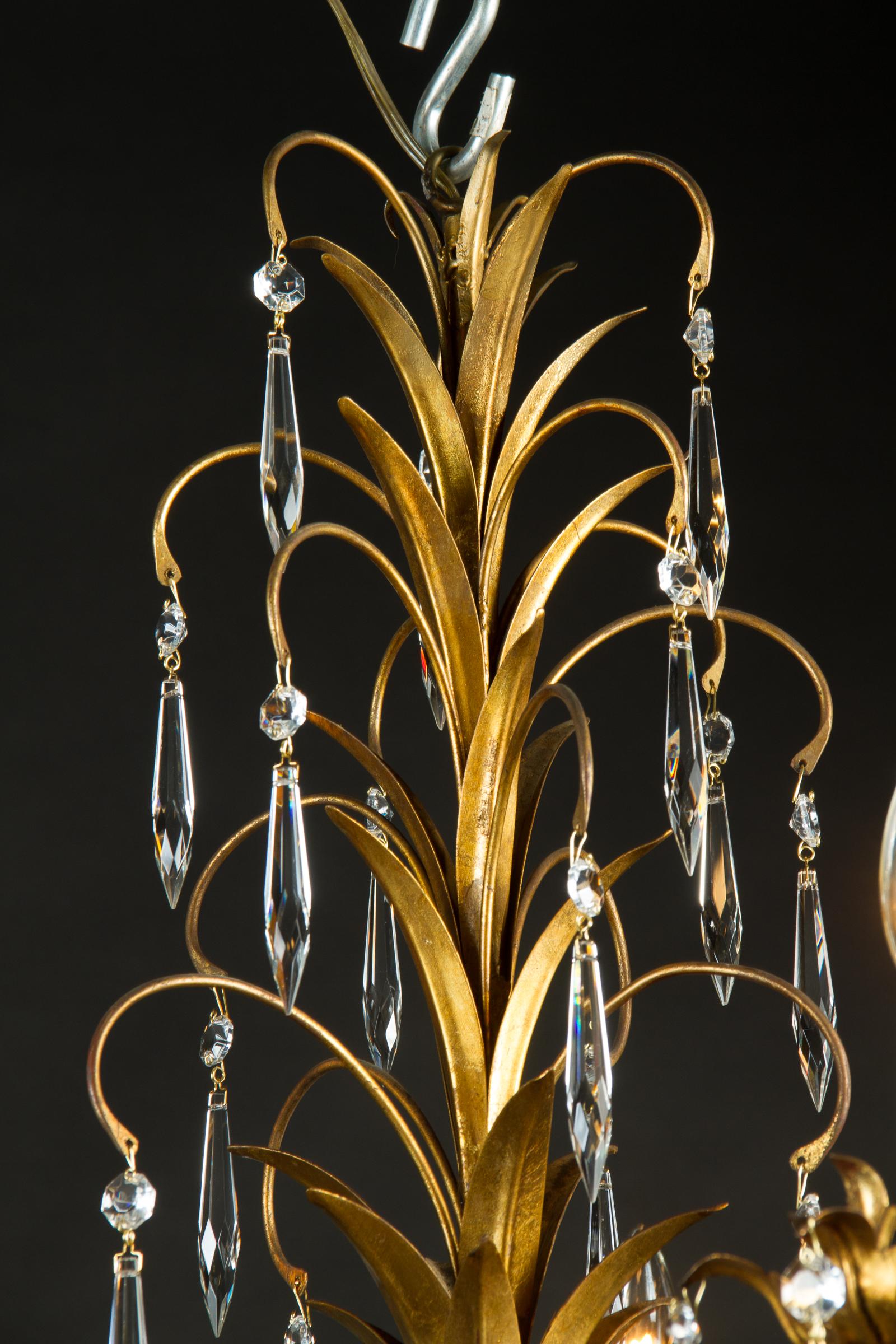 This beautiful Louis XV chandelier is made of gilded tole, gold plated tin, and draped with beautiful crystals, joining our collection from Italy. The piece dates back to the Mid-20th Century, circa 1950, and offers a unique shape with a foliate