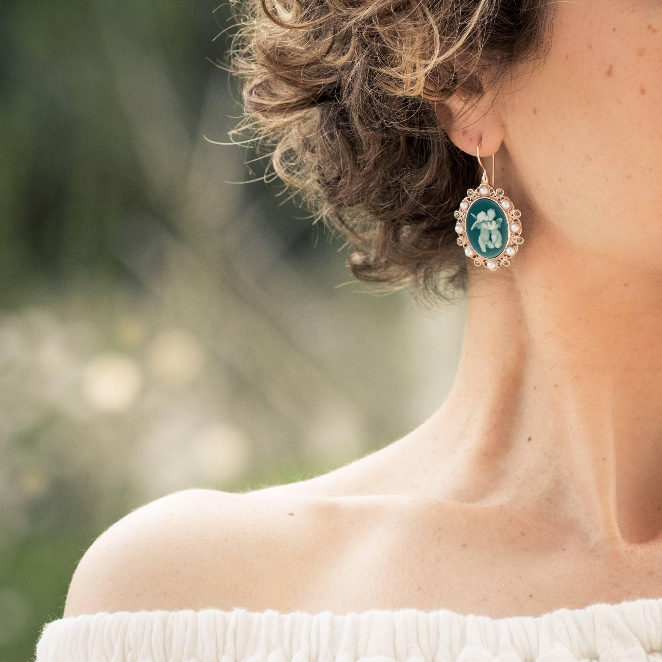 Earrings in rose vermeil, silver and rose gold.
Large sleepers earrings, each consists of a cameo on green glass paste in closed setting, representing 2 cherubs surrounded by crystals and glass pearls. The clasp is a gooseneck with safety